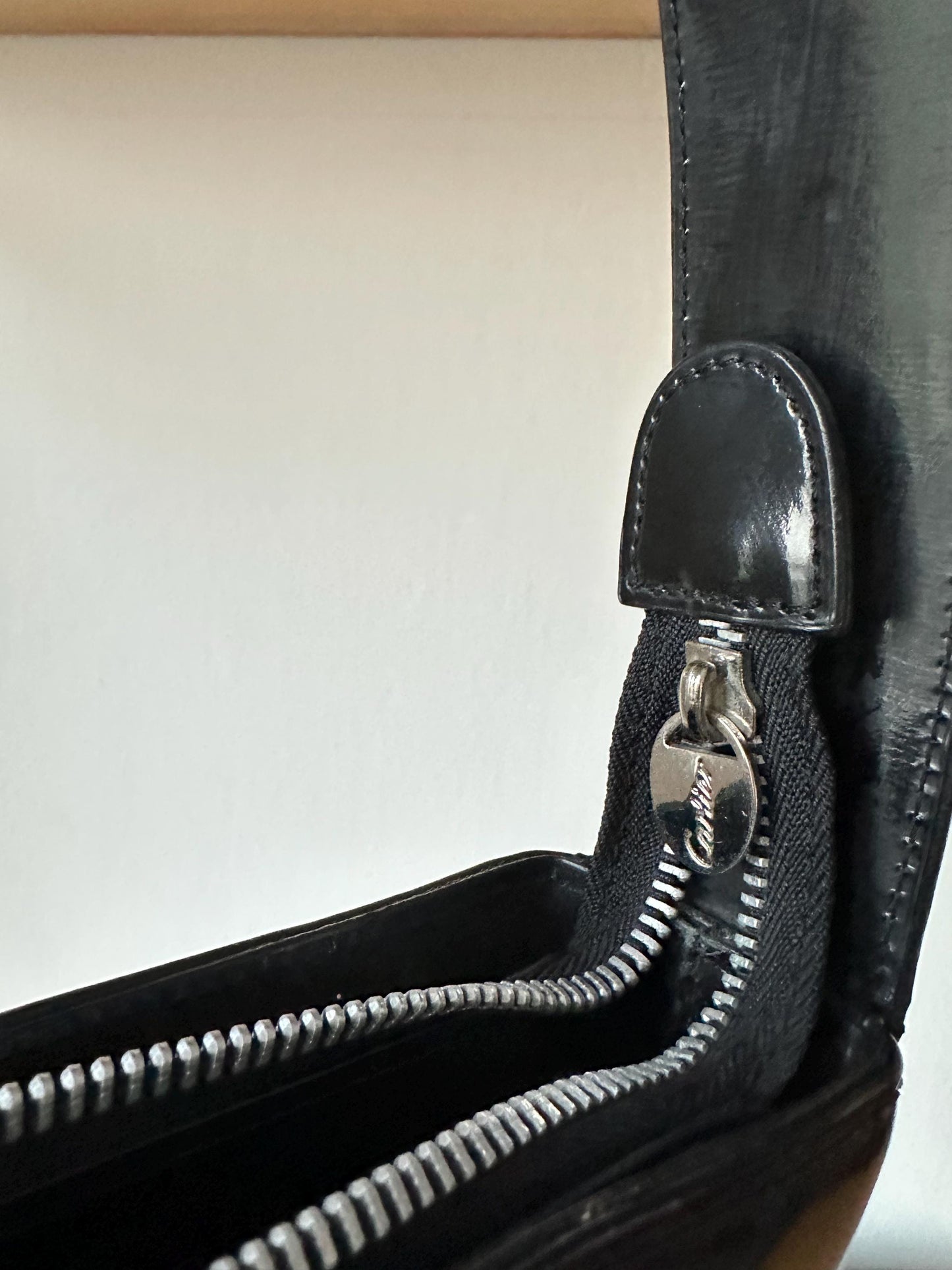 A close-up view of a black leather handbag with a zipper closure.