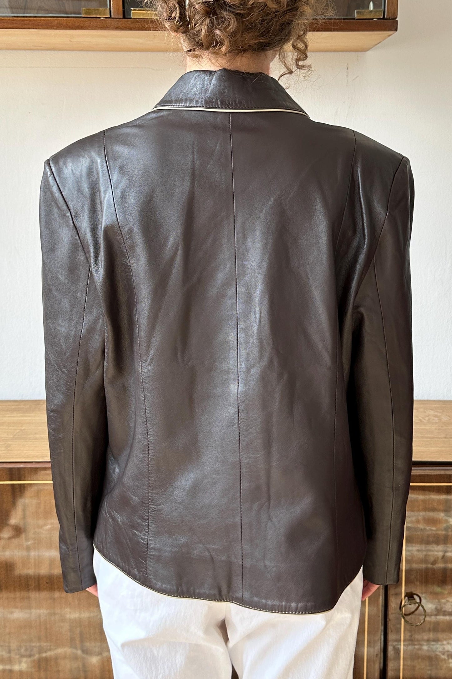 the back view of a person wearing a brown leather jacket.