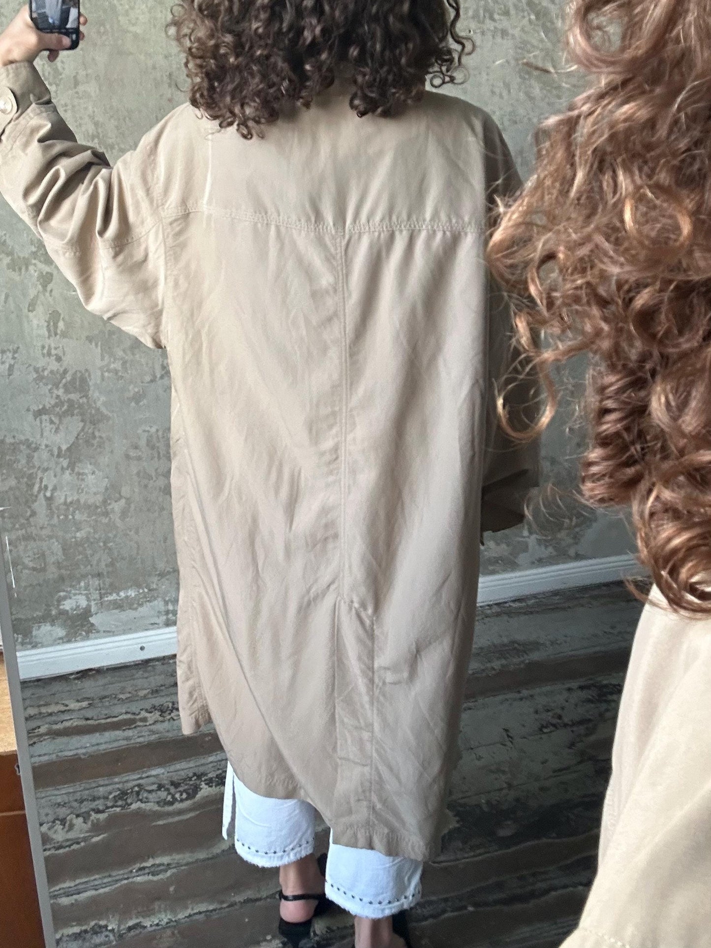 a person taking a selfie in front of a mirror, with their back facing the camera.
