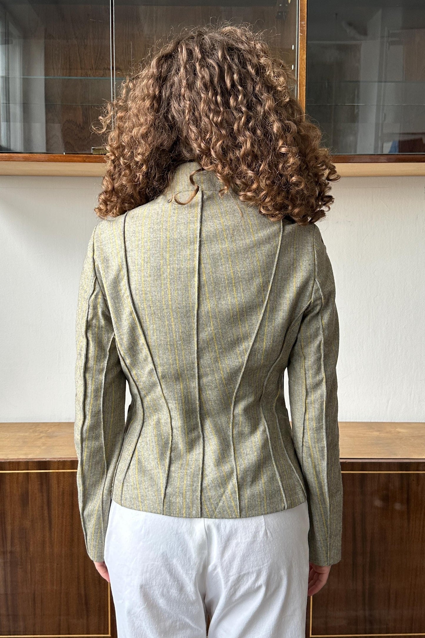 the back view of a person wearing a gray jacket with vertical stripes.