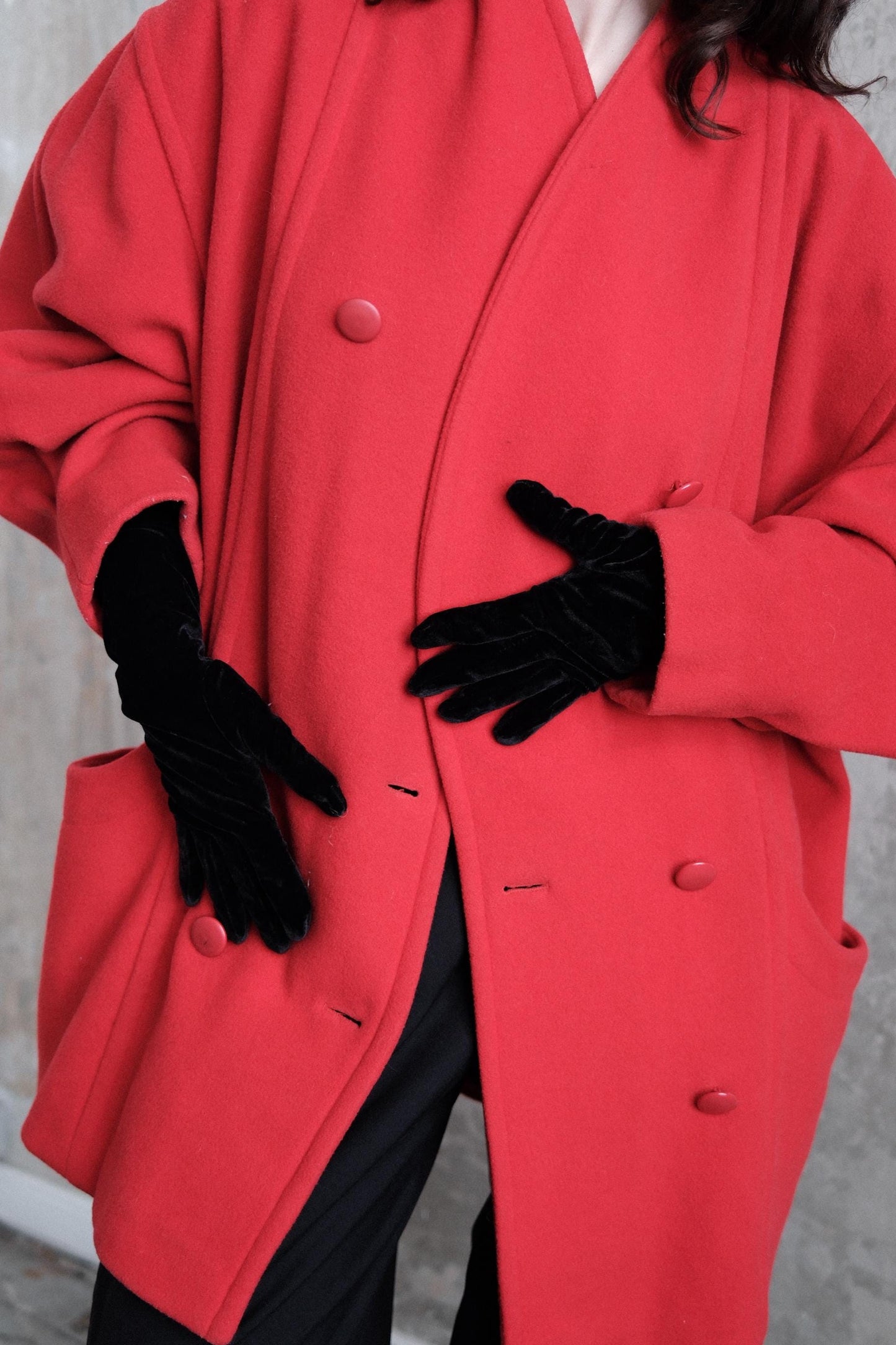 A person wearing a bright red coat and black gloves is shown in the image.