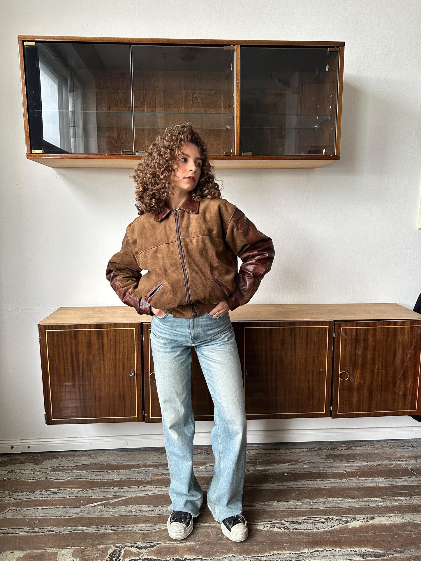 A person standing in a room with wooden cabinets and a glass display case.