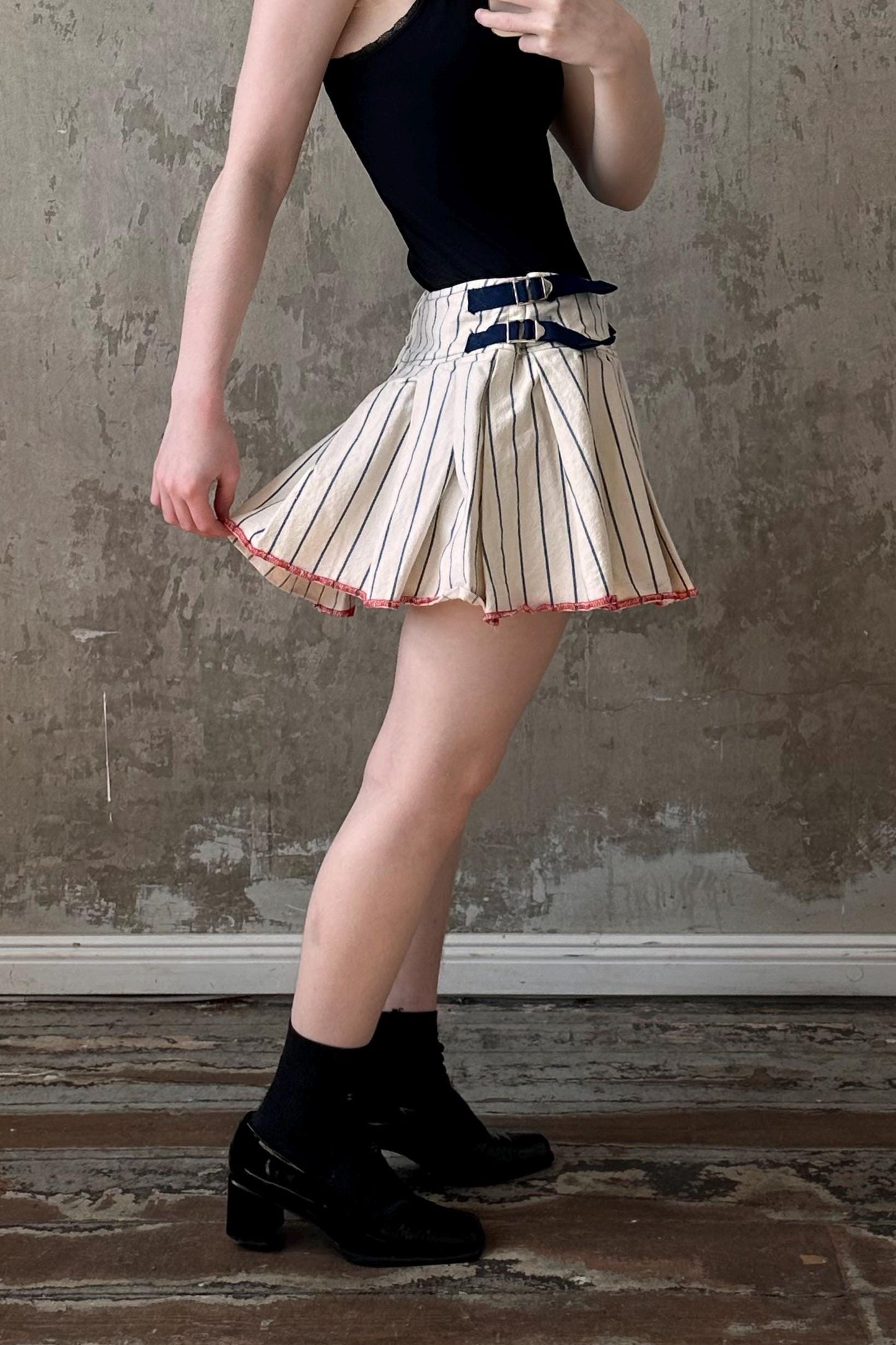 a woman wearing a skirt and a black tank top