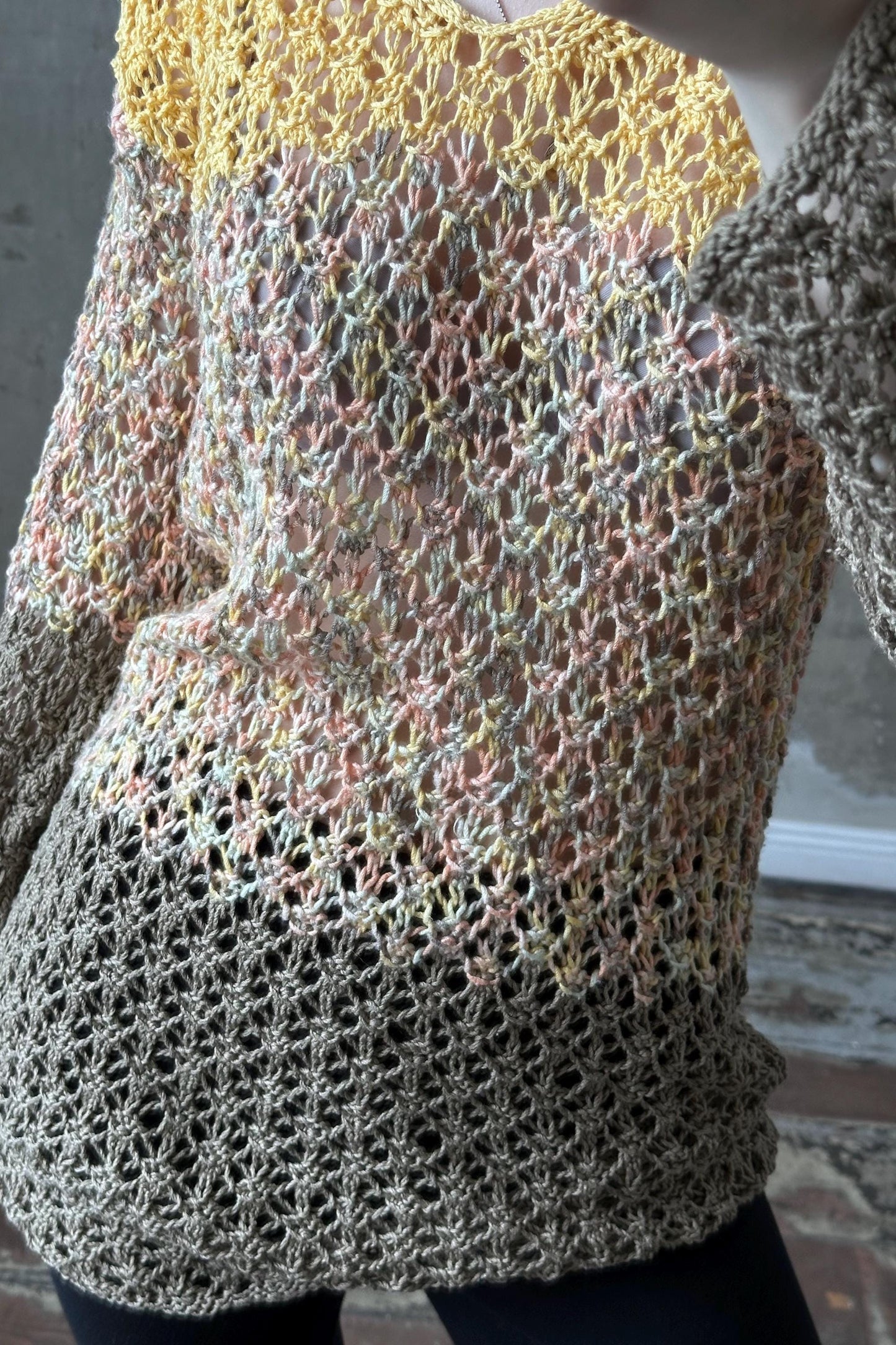 A close-up image of a knitted or crocheted sweater with a multicolored, textured pattern.