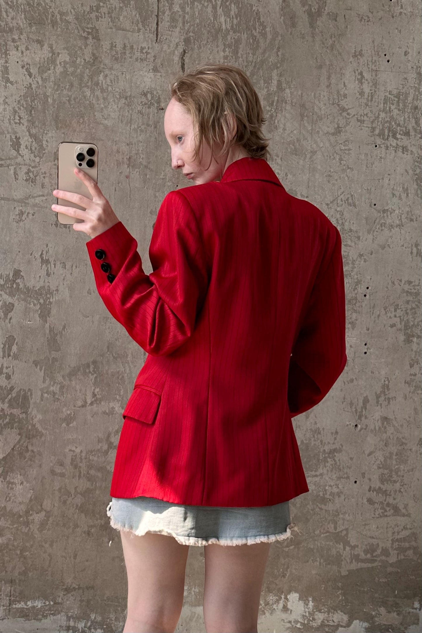 a woman in a red jacket taking a picture with her cell phone