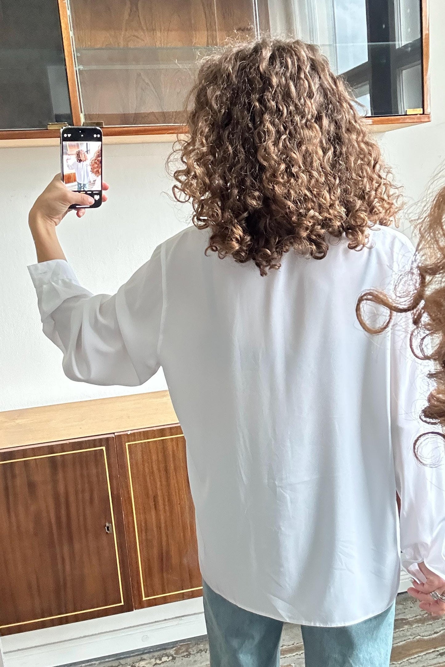 a person taking a selfie with a smartphone, capturing their back view.
