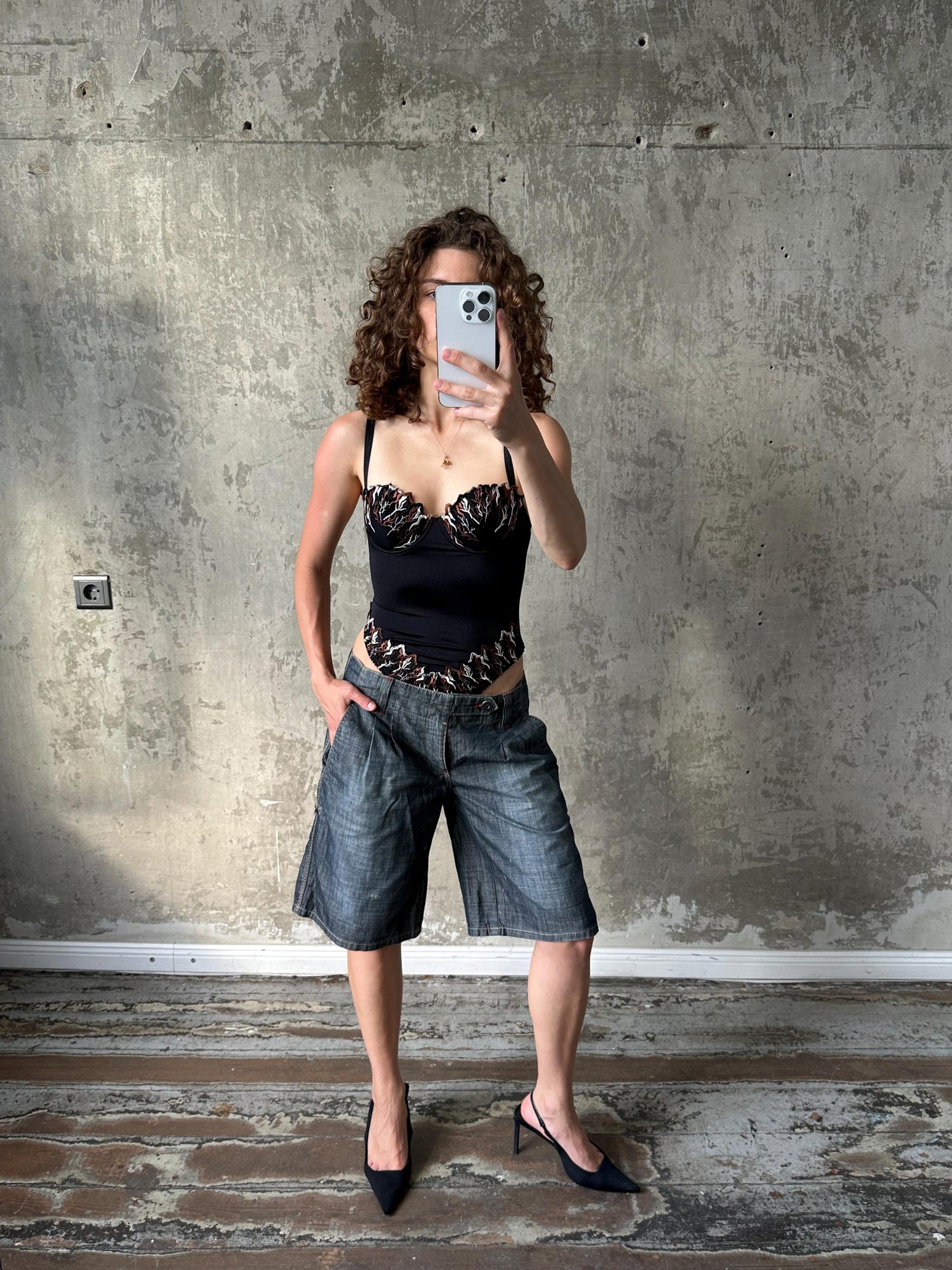 A woman is taking a selfie with her phone, standing in front of a concrete wall.