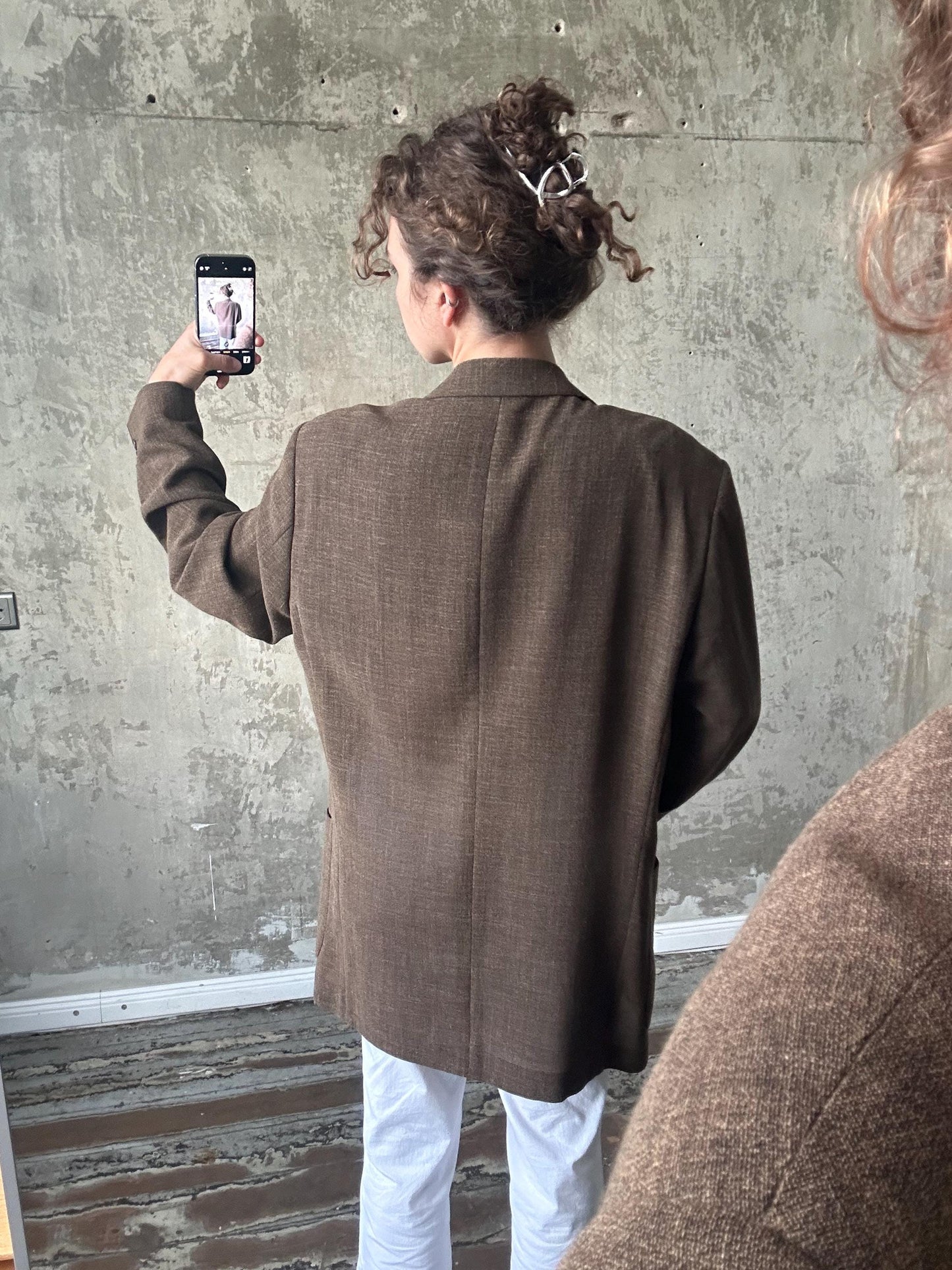 A person is taking a selfie with a smartphone, capturing their back view.