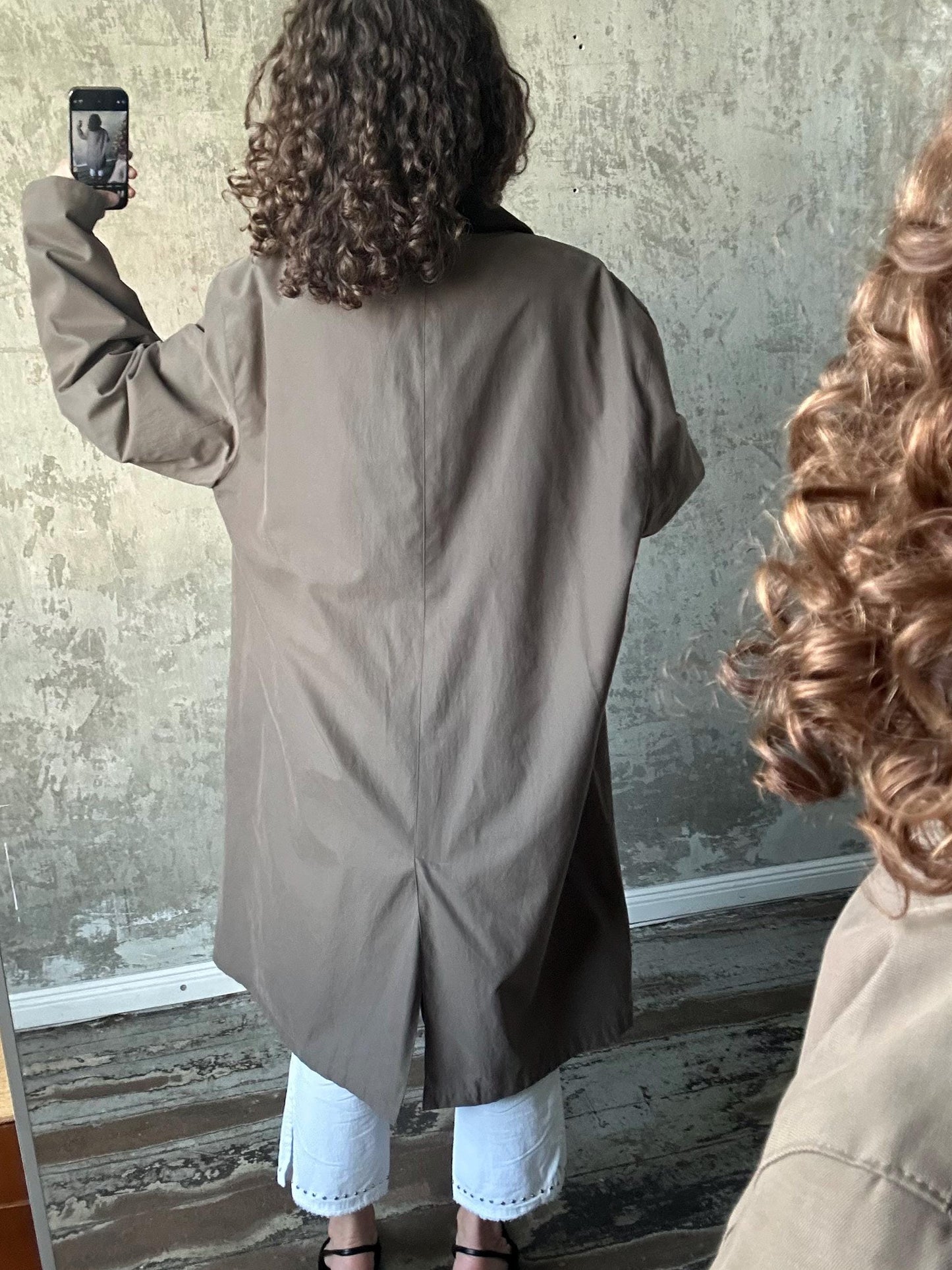 a person taking a selfie with a smartphone, capturing their reflection in a mirror.
