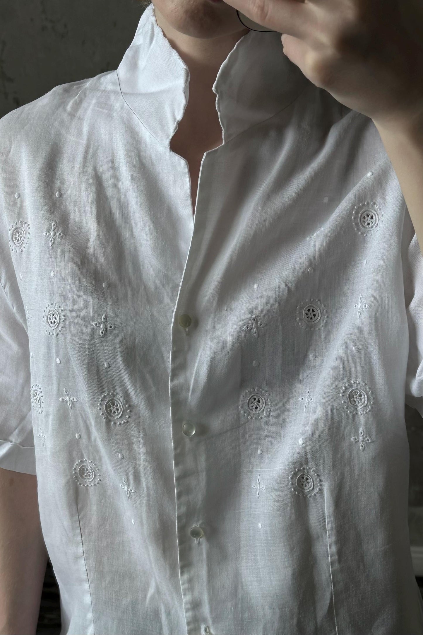 A close-up of a person wearing a white shirt with small embroidered circles on the front.