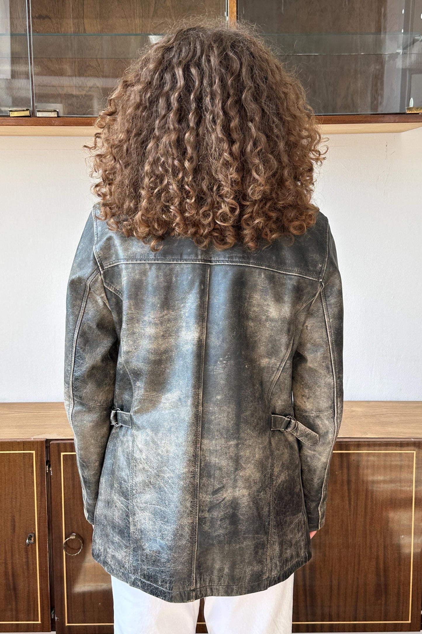 the back of a person wearing a gray leather jacket with curly hair.