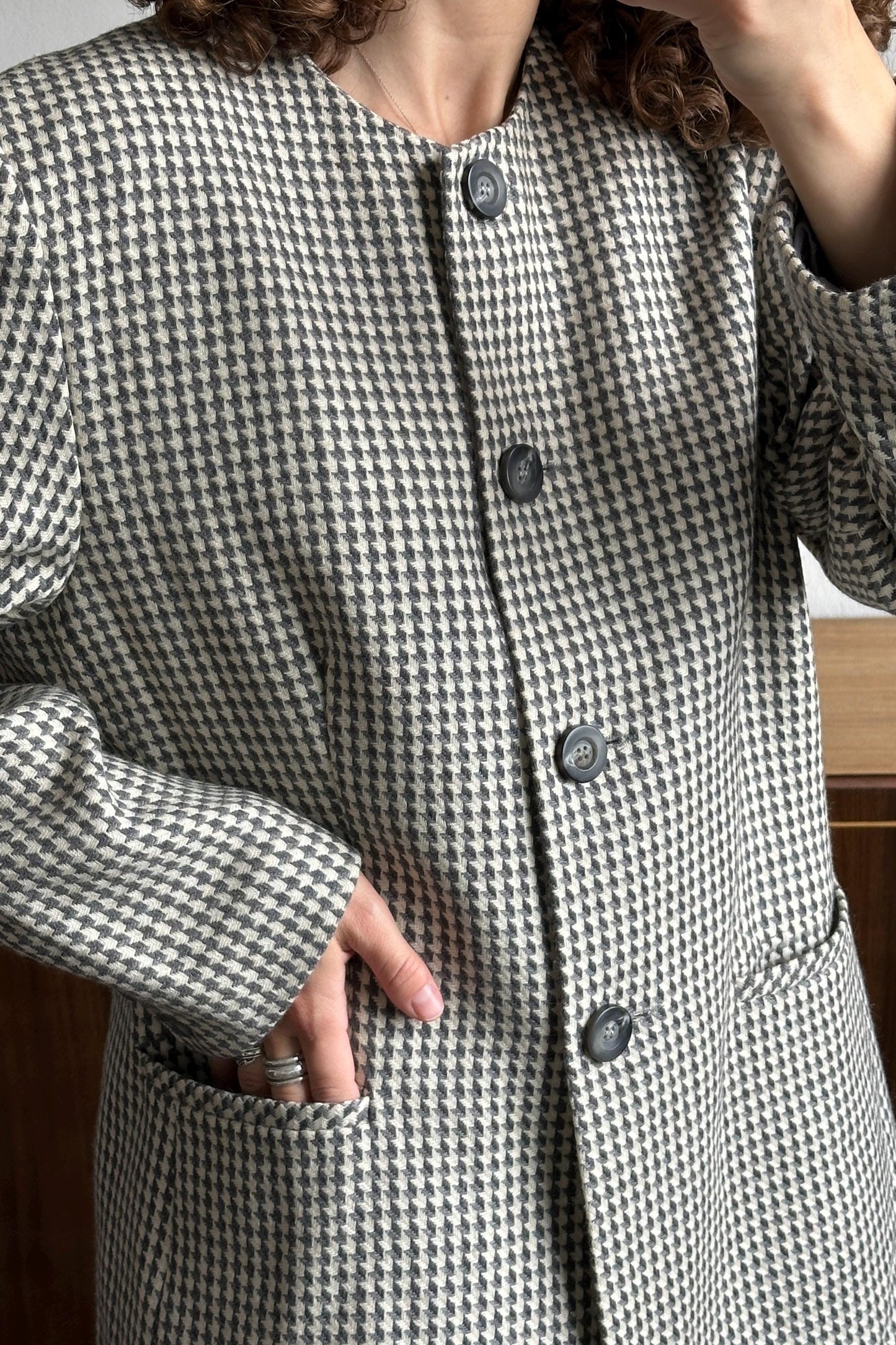 A close-up of a person wearing a black and white checkered jacket with three buttons.