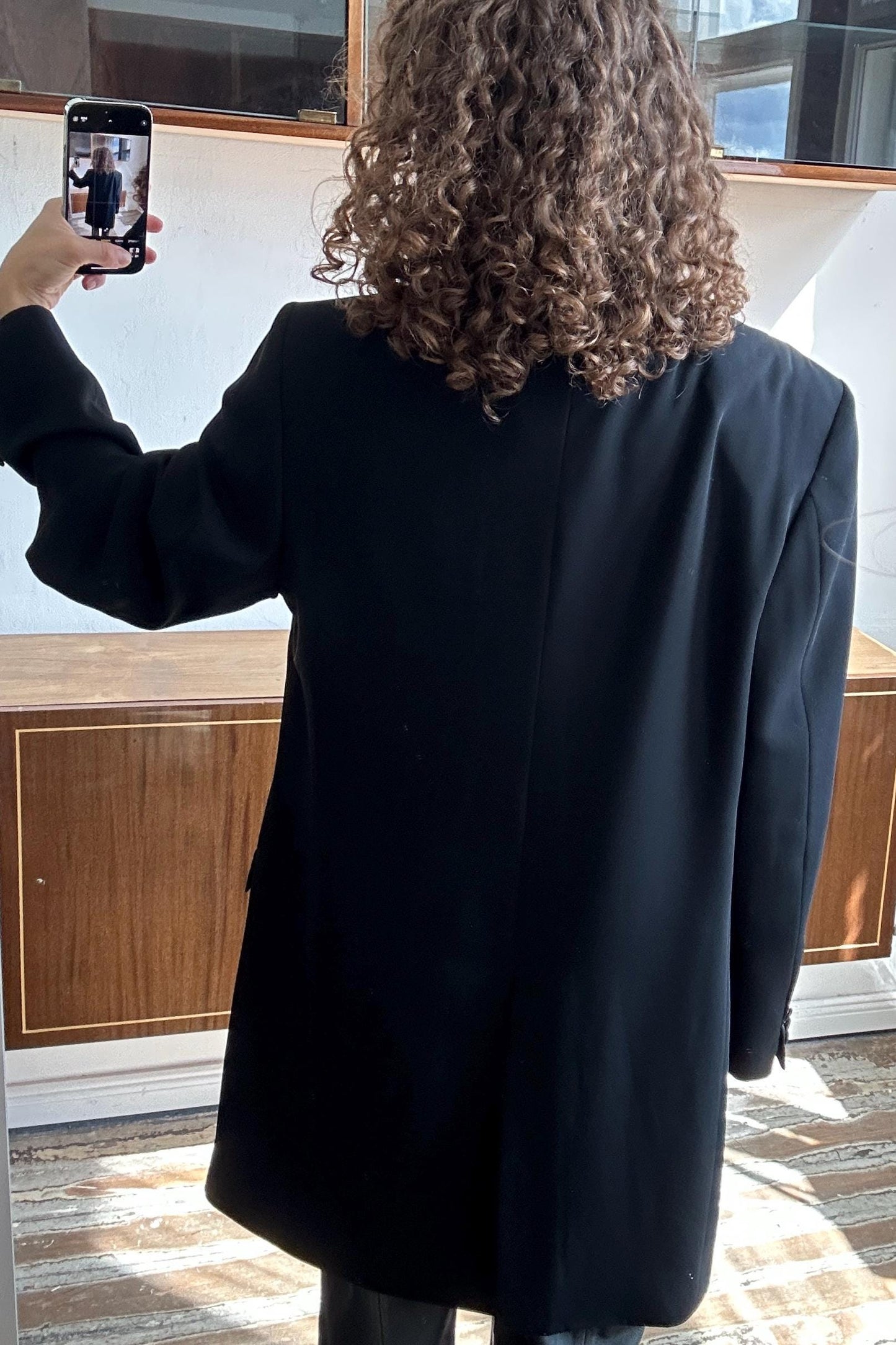 a person taking a selfie with a smartphone, capturing their back view.