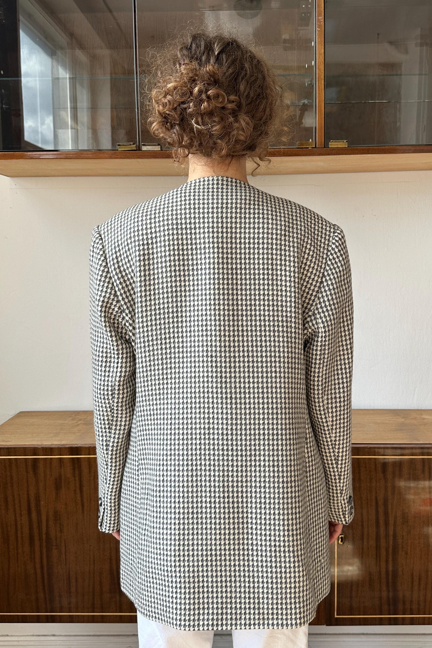 the back of a person wearing a black and white checkered jacket, standing in front of a glass display case.