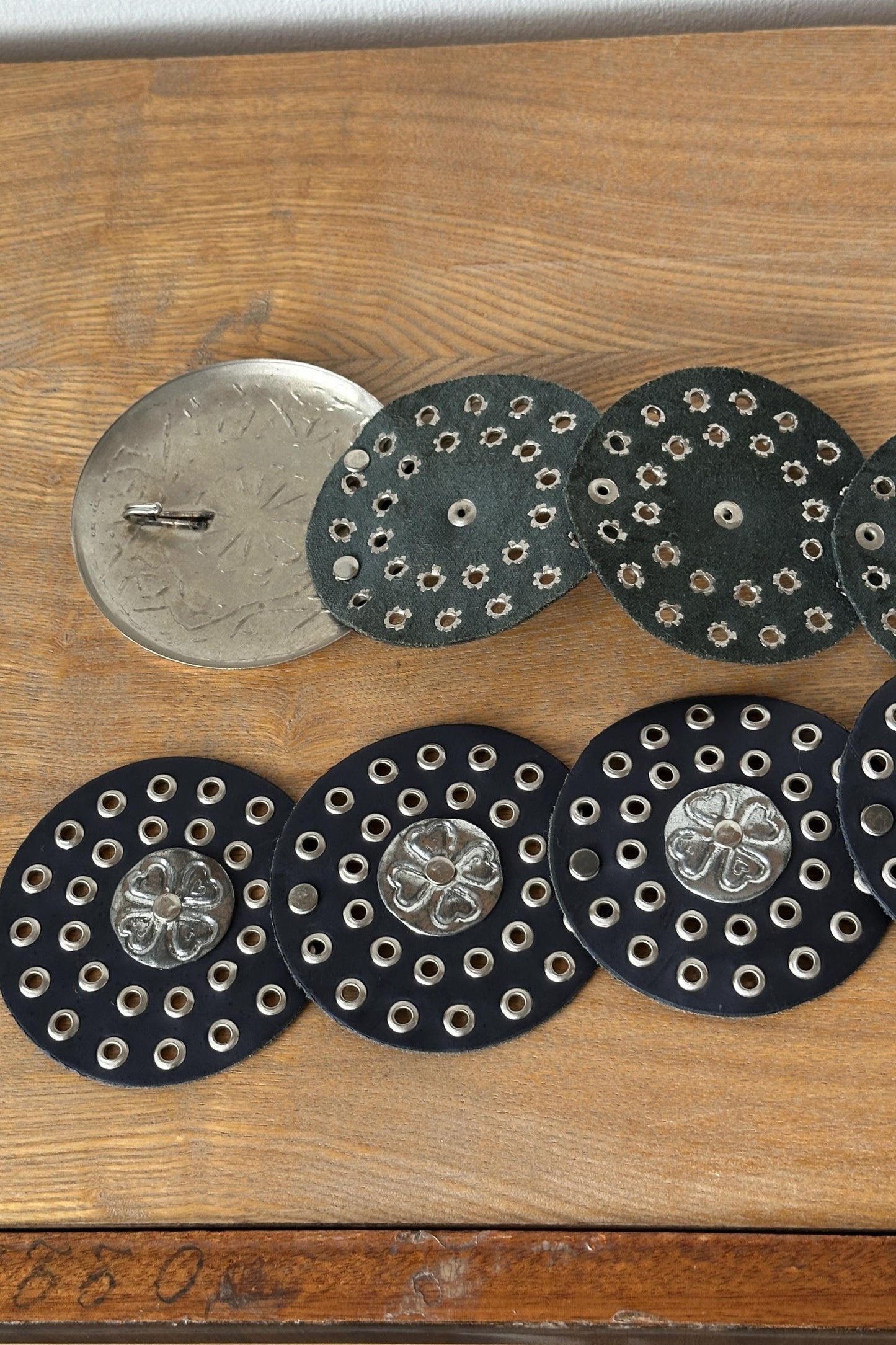 a collection of circular metal pieces with holes arranged on a wooden surface.