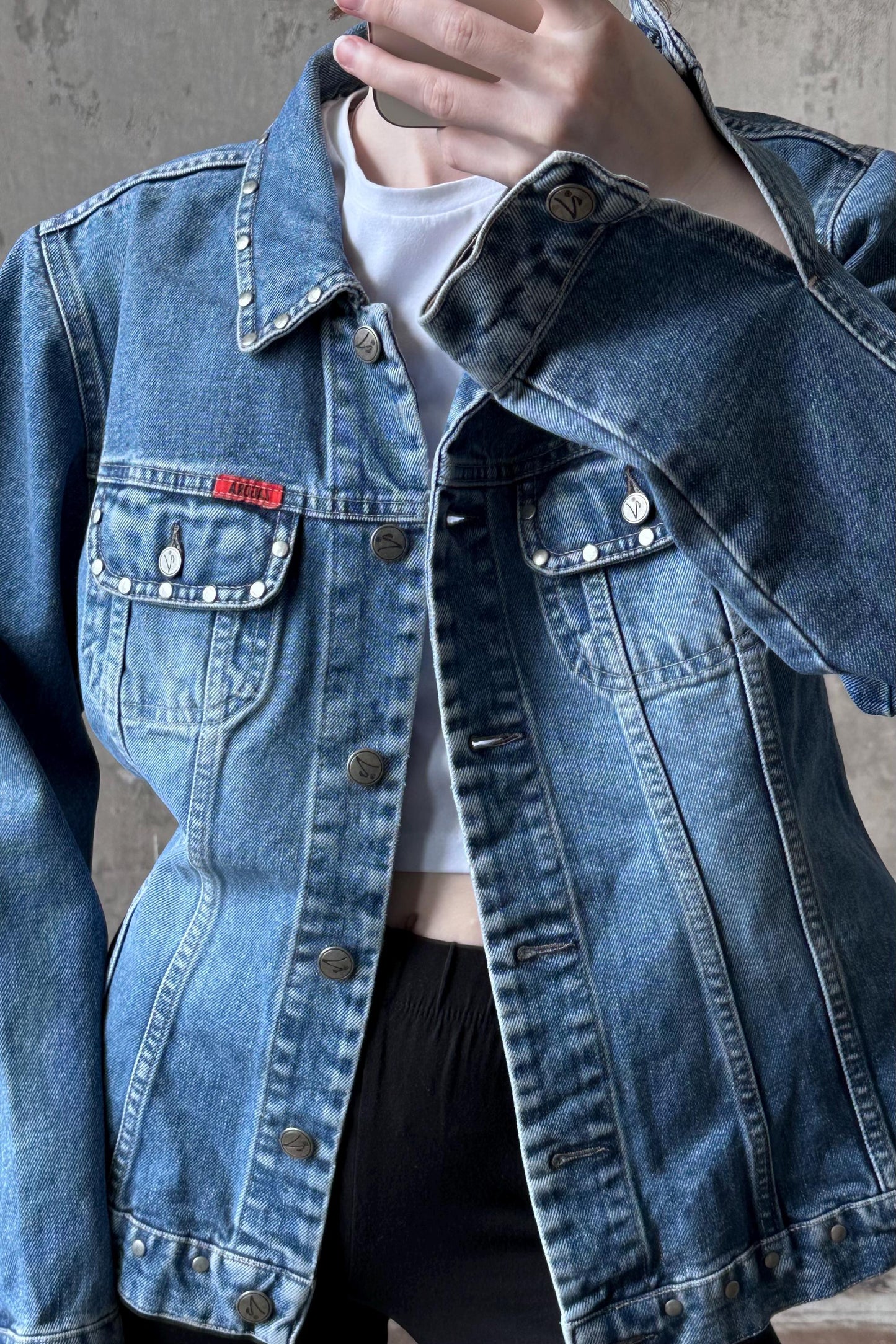 A person wearing a blue denim jacket with a white t-shirt underneath.