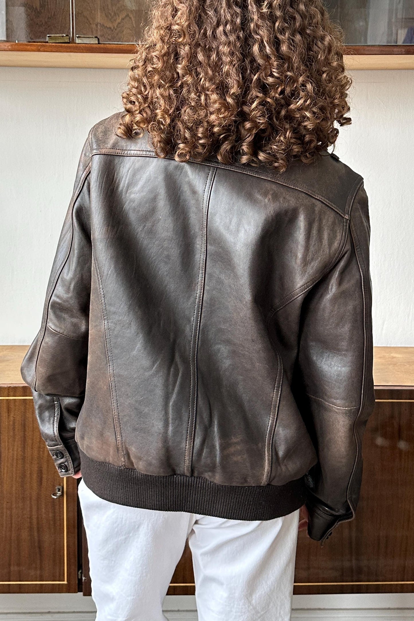 the back of a person wearing a brown leather jacket.