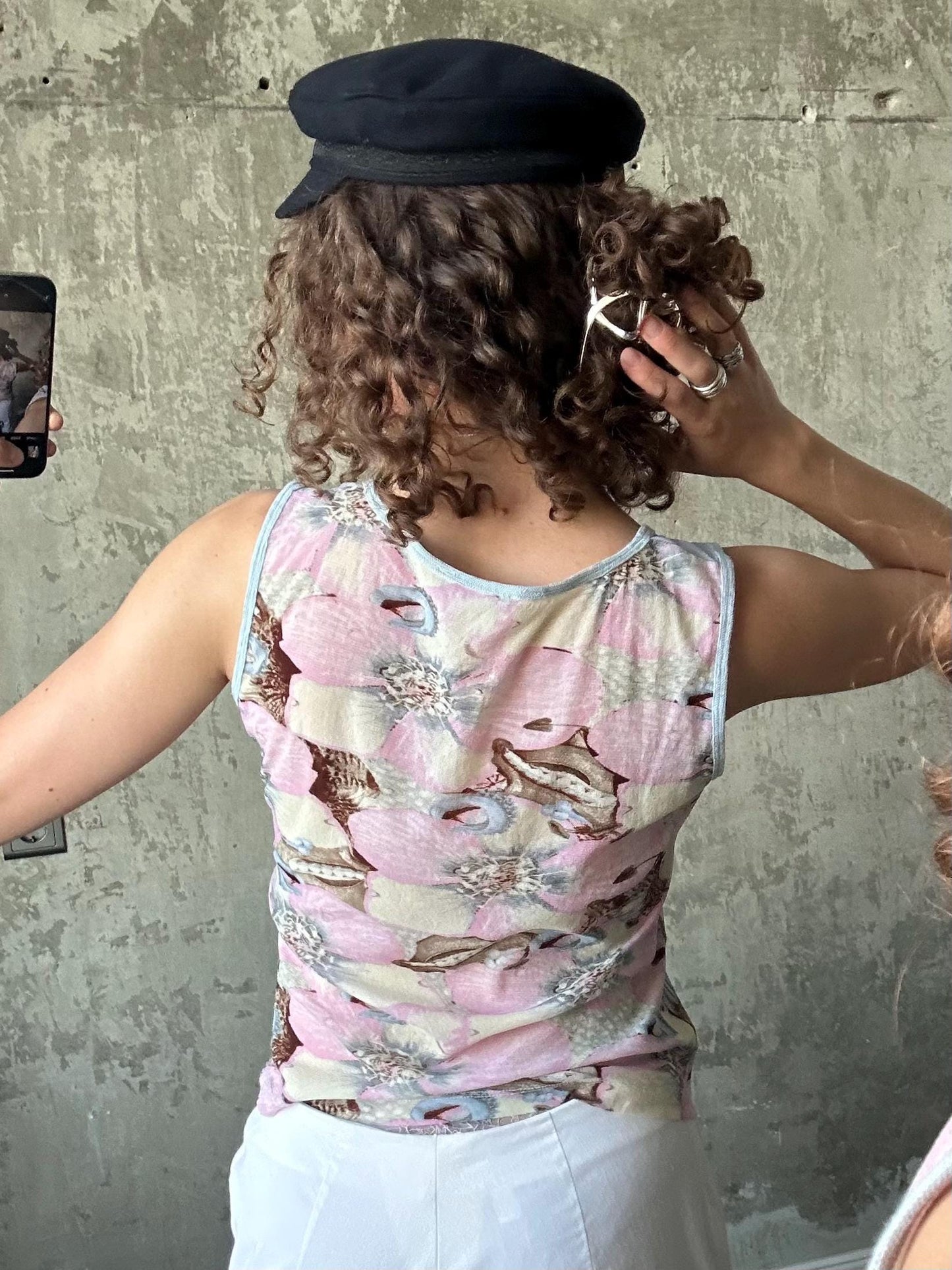 a person taking a selfie in front of a concrete wall, with their back facing the camera.
