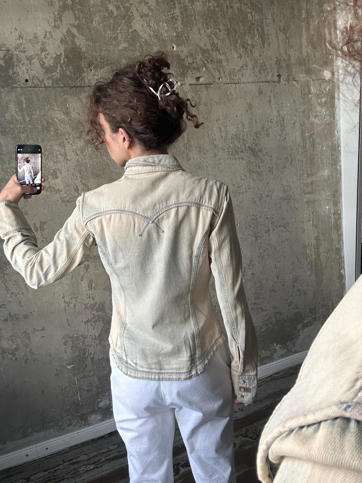 A person is taking a selfie with a smartphone, capturing their back view.