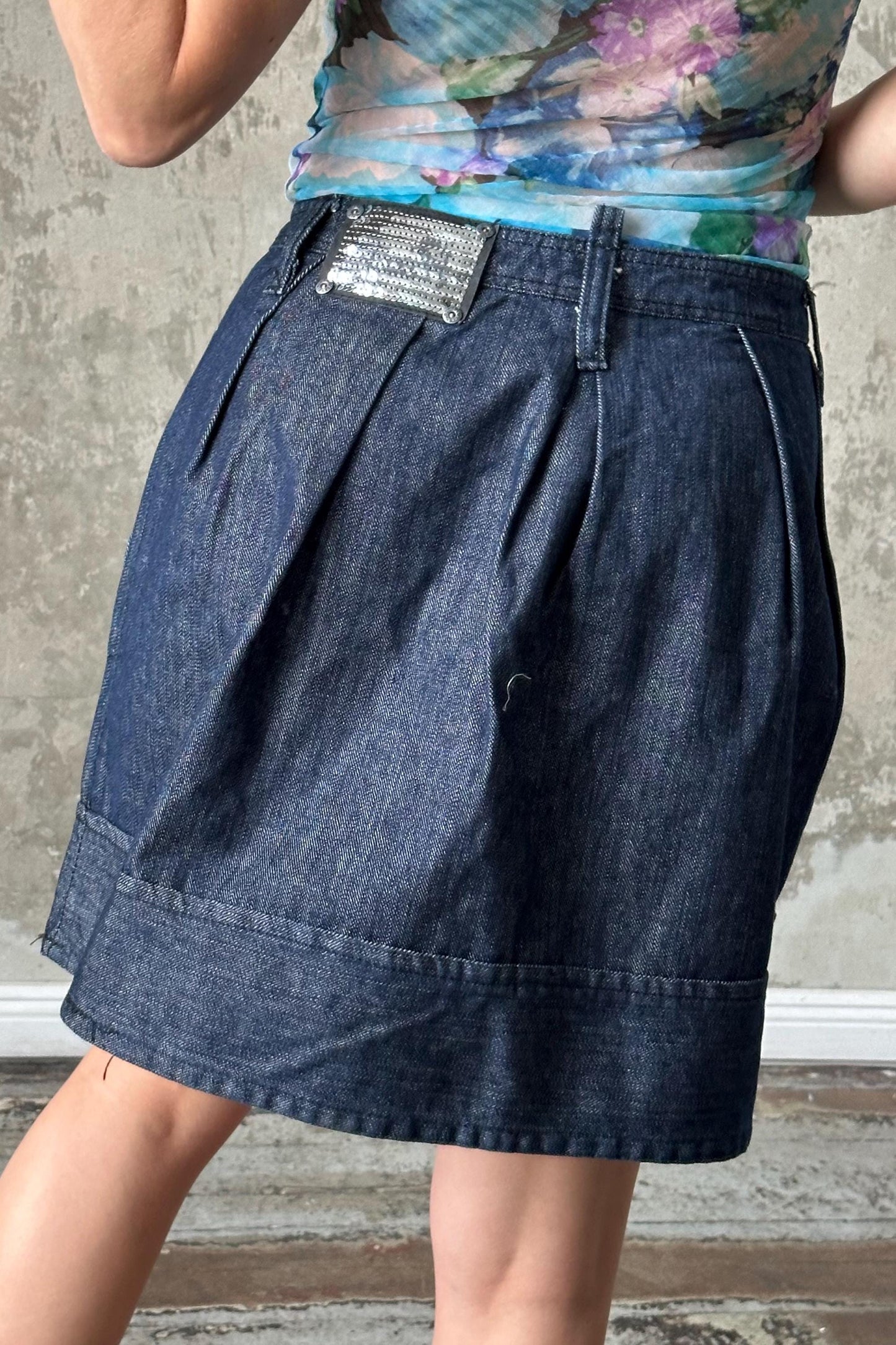 A woman wearing a blue denim skirt with a floral pattern on the top.