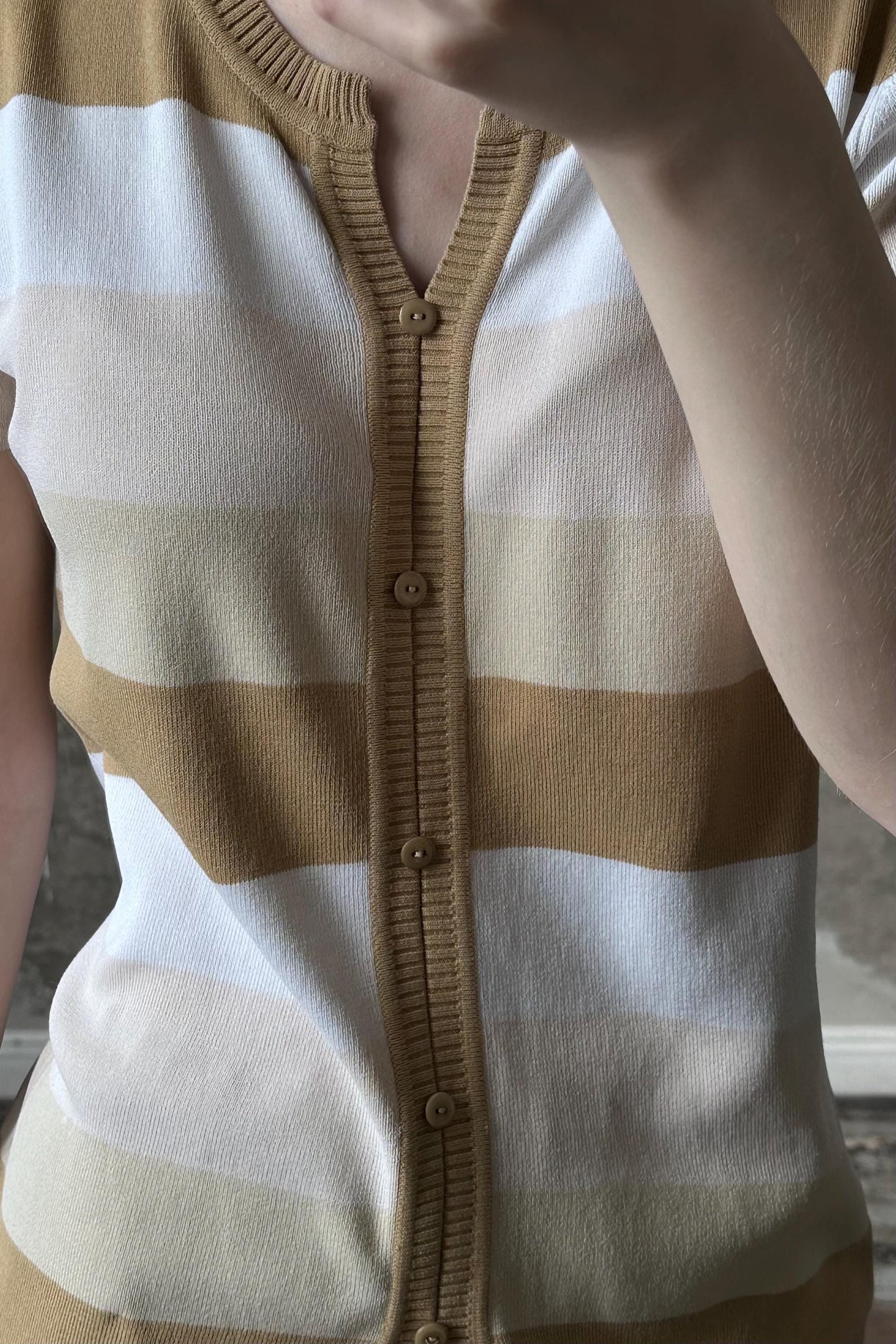 a close-up view of a person wearing a striped cardigan with a button-down front.