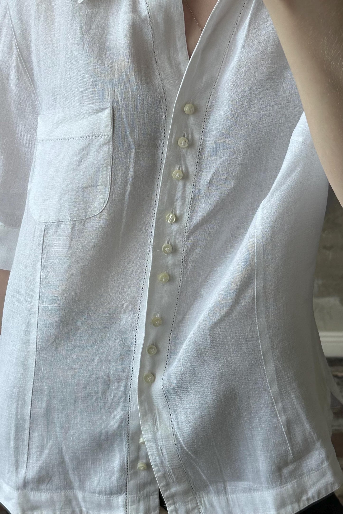 A close-up view of a person wearing a white button-up shirt with a pocket and buttons.