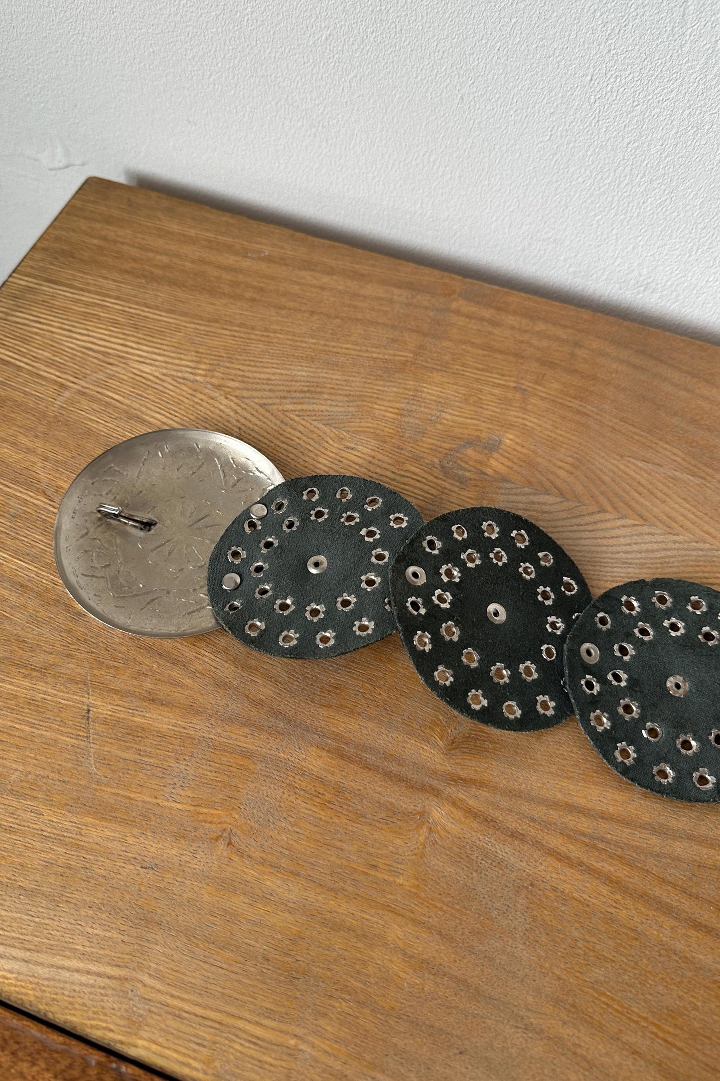 a wooden surface with three circular objects, each with a hole in the center, arranged in a row.