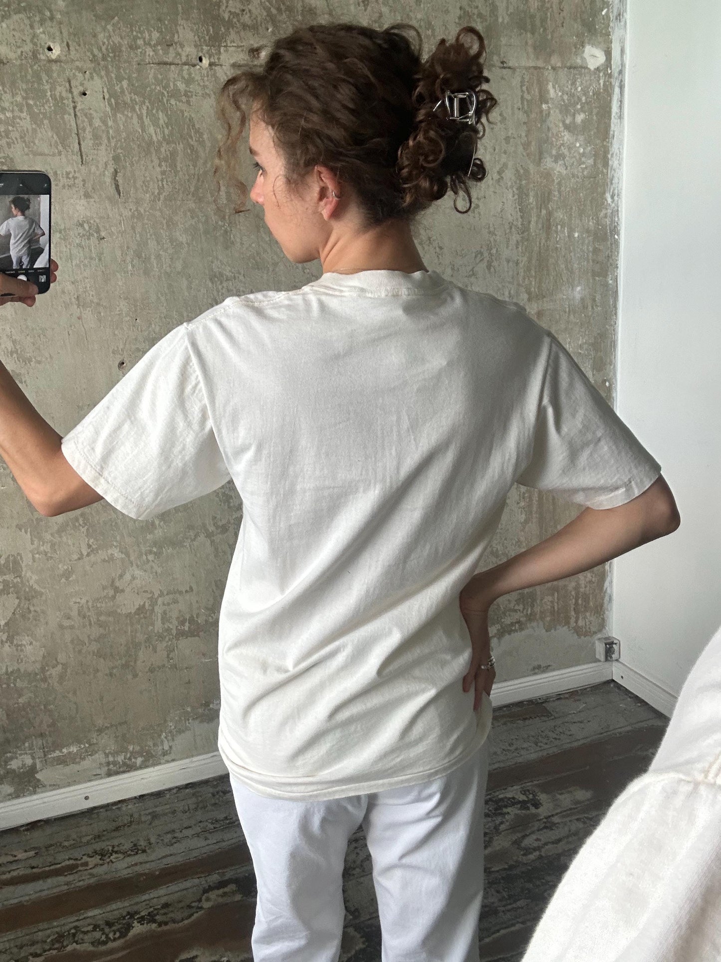 A person is taking a selfie with a smartphone, capturing their back view.