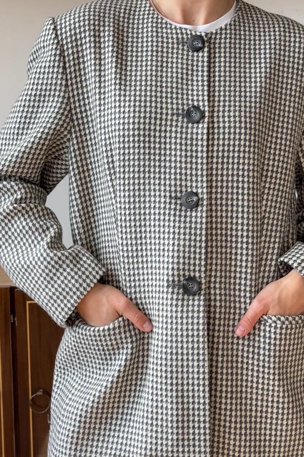A close-up of a person wearing a black and white checkered coat with three buttons.