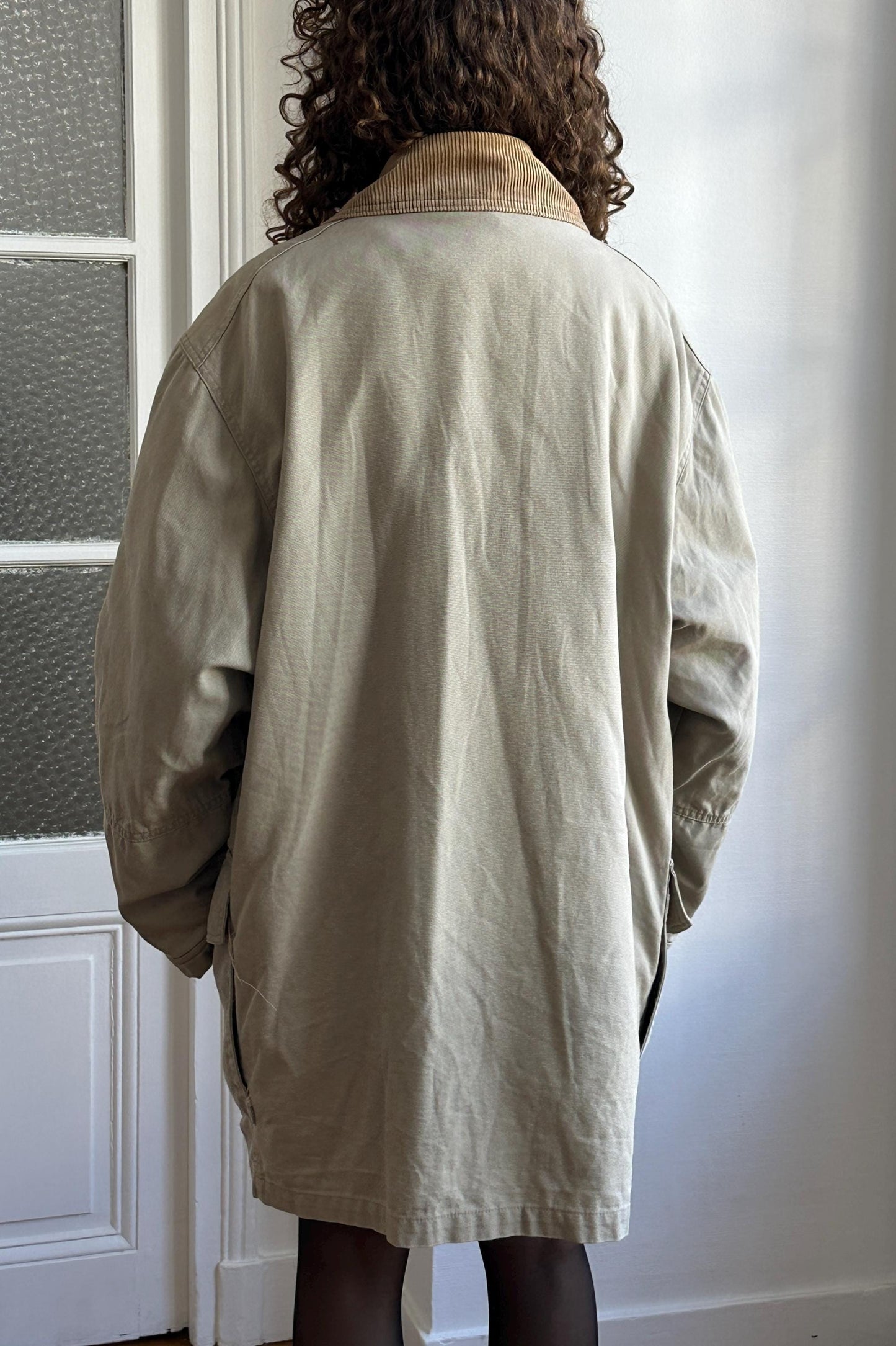 the back of a person wearing a beige coat with a brown collar.