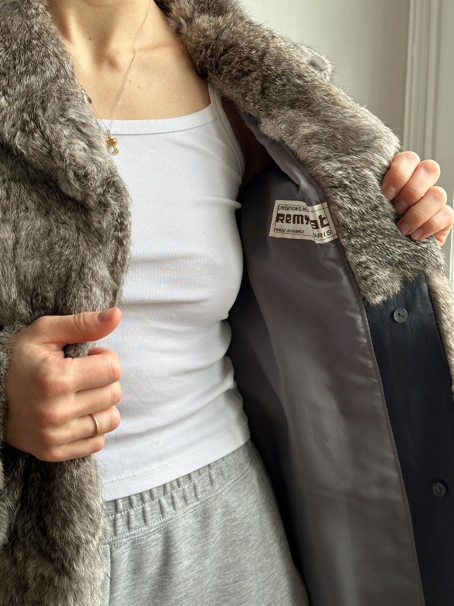 A person is lying down, wearing a gray fur coat and a white shirt.