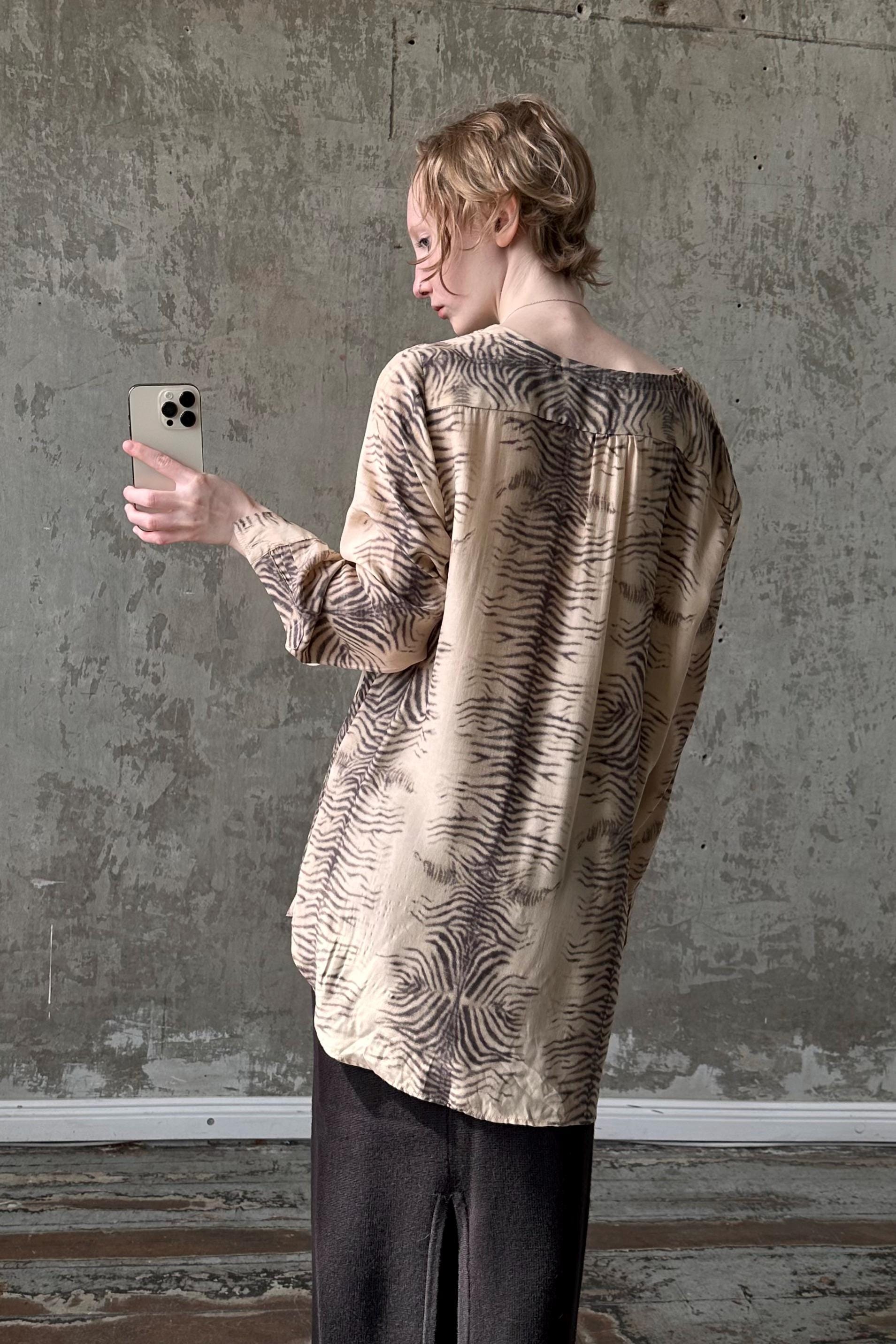 a woman standing in front of a wall holding a cell phone