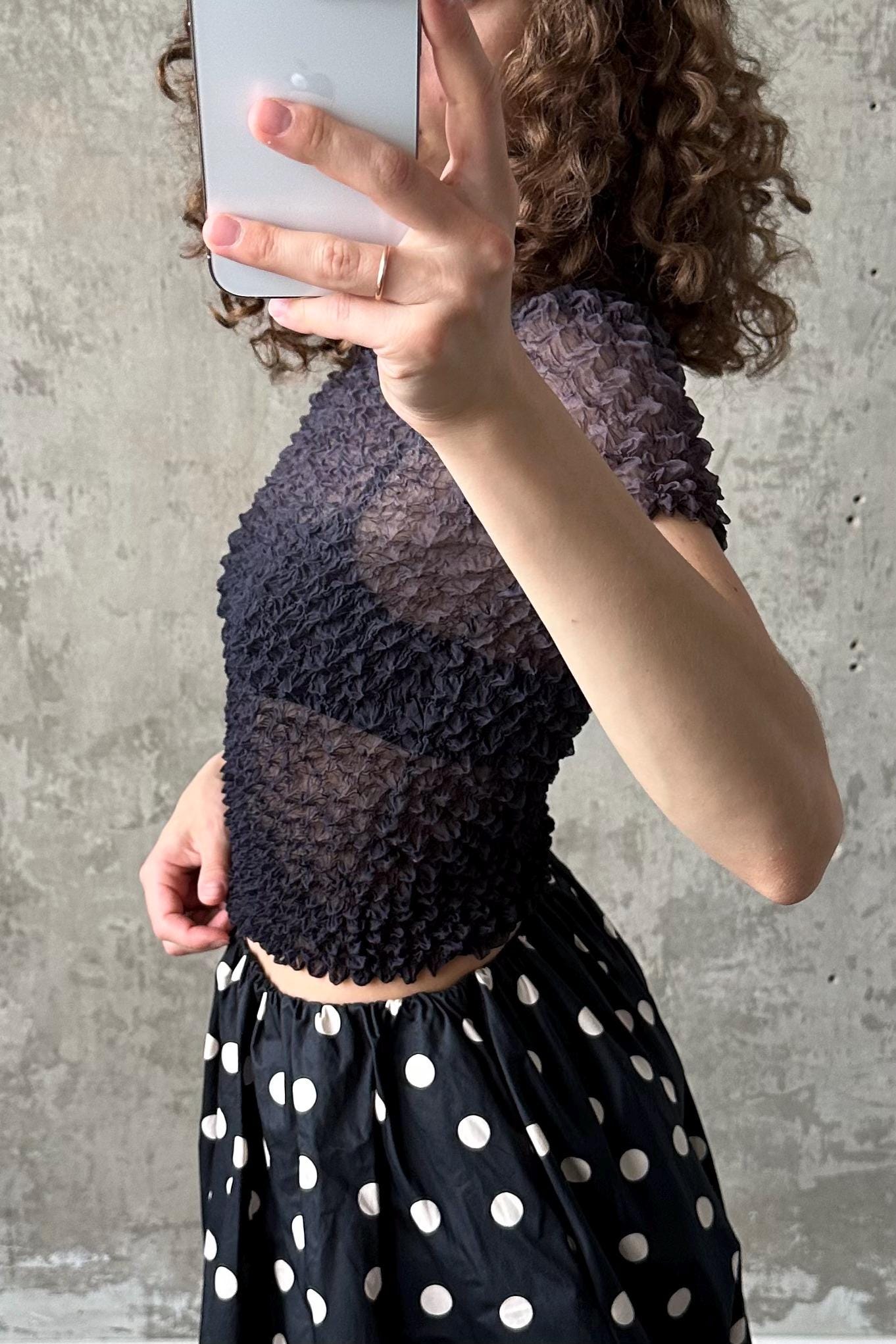 A woman is taking a selfie with a smartphone, holding the device up to her face to capture her image.
