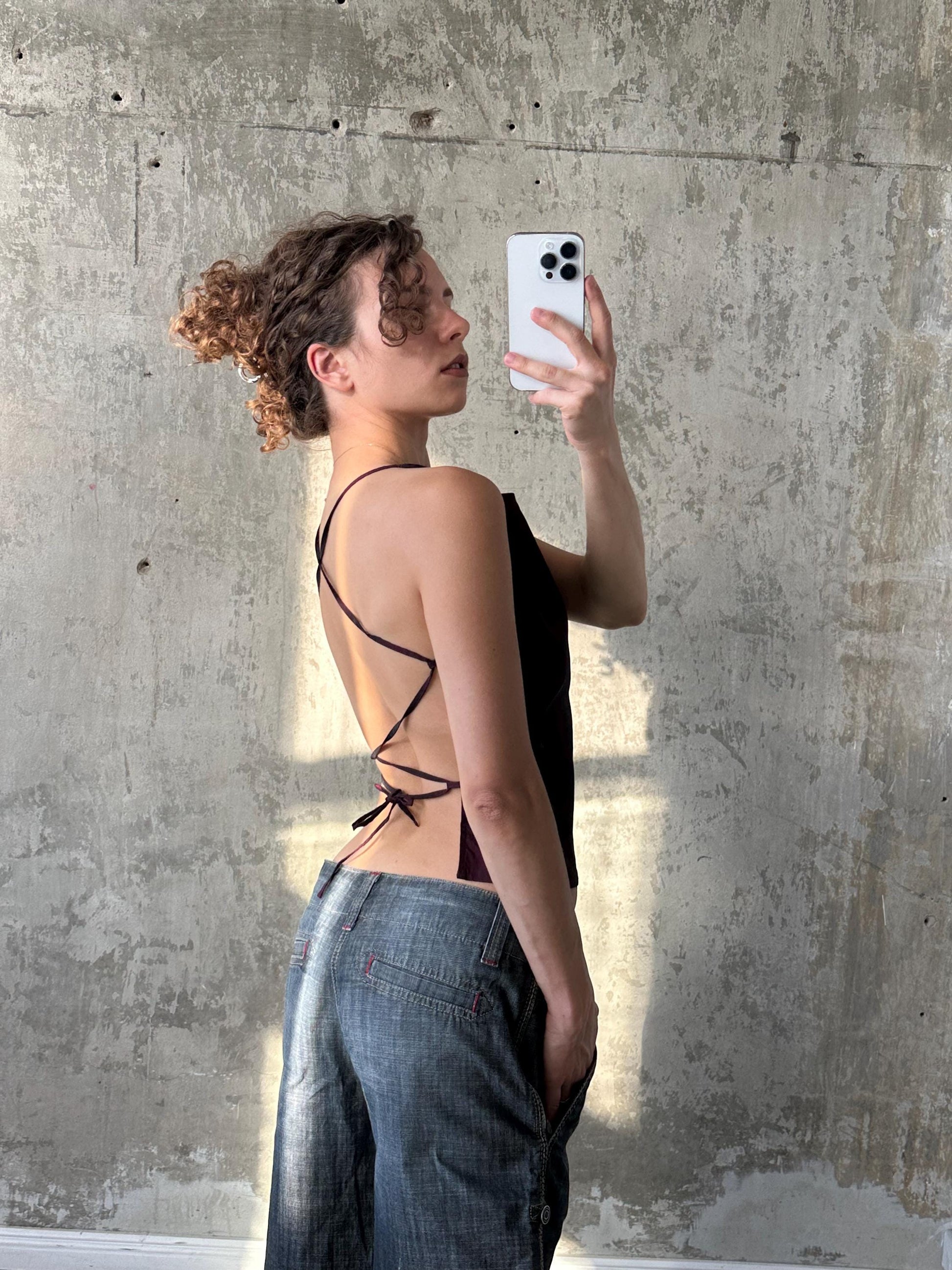 A woman is taking a selfie with her iPhone, holding the device up to her face and looking at the camera.