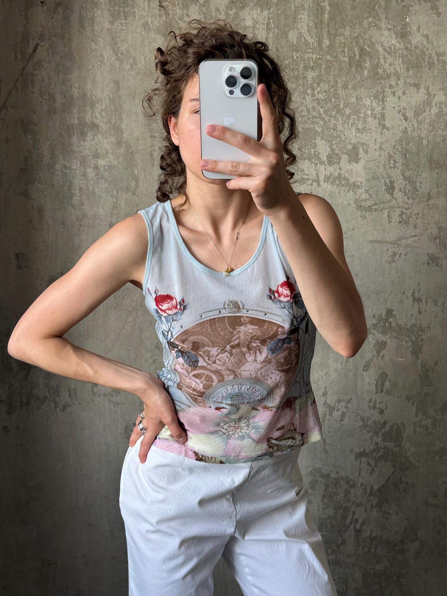 A woman is taking a selfie with her iPhone, holding it up to her face against a concrete wall.