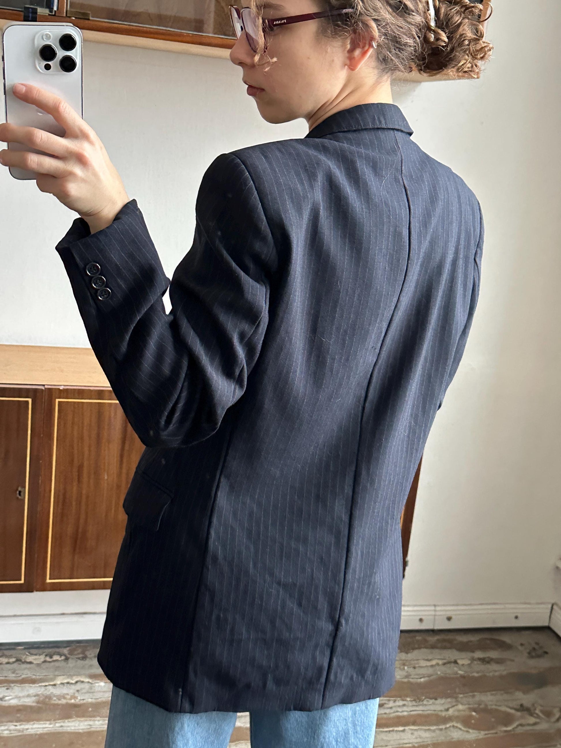 A person wearing a dark suit jacket is leaning over a wooden cabinet, with a smartphone visible in the background.