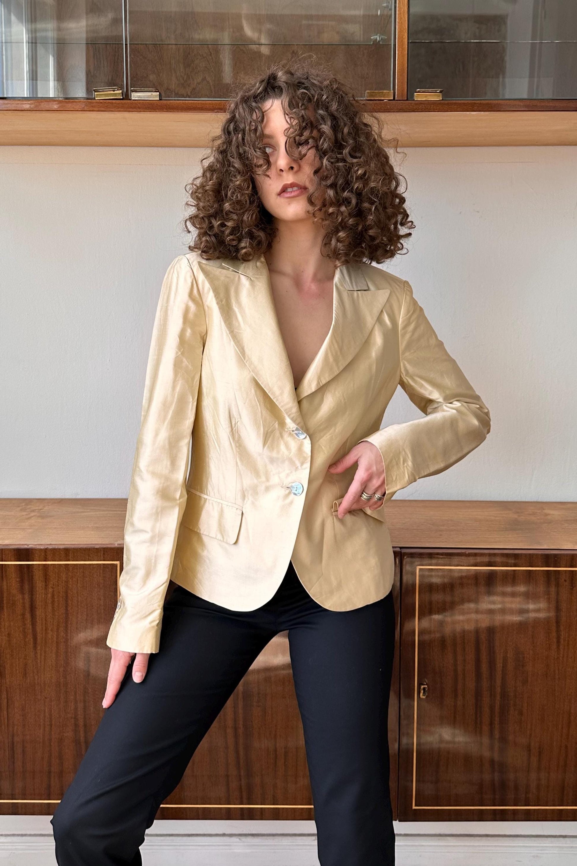 a woman with curly hair standing in front of a cabinet