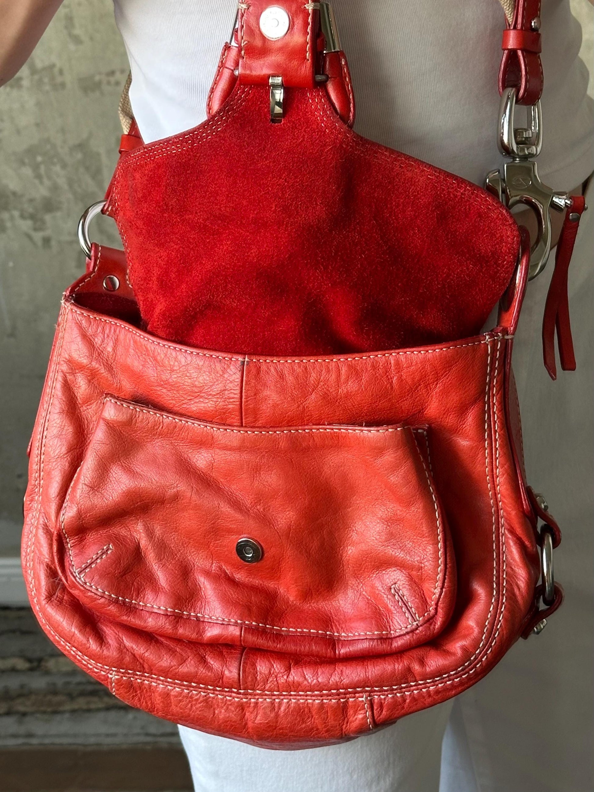 A red leather handbag with a red zipper and metal hardware.