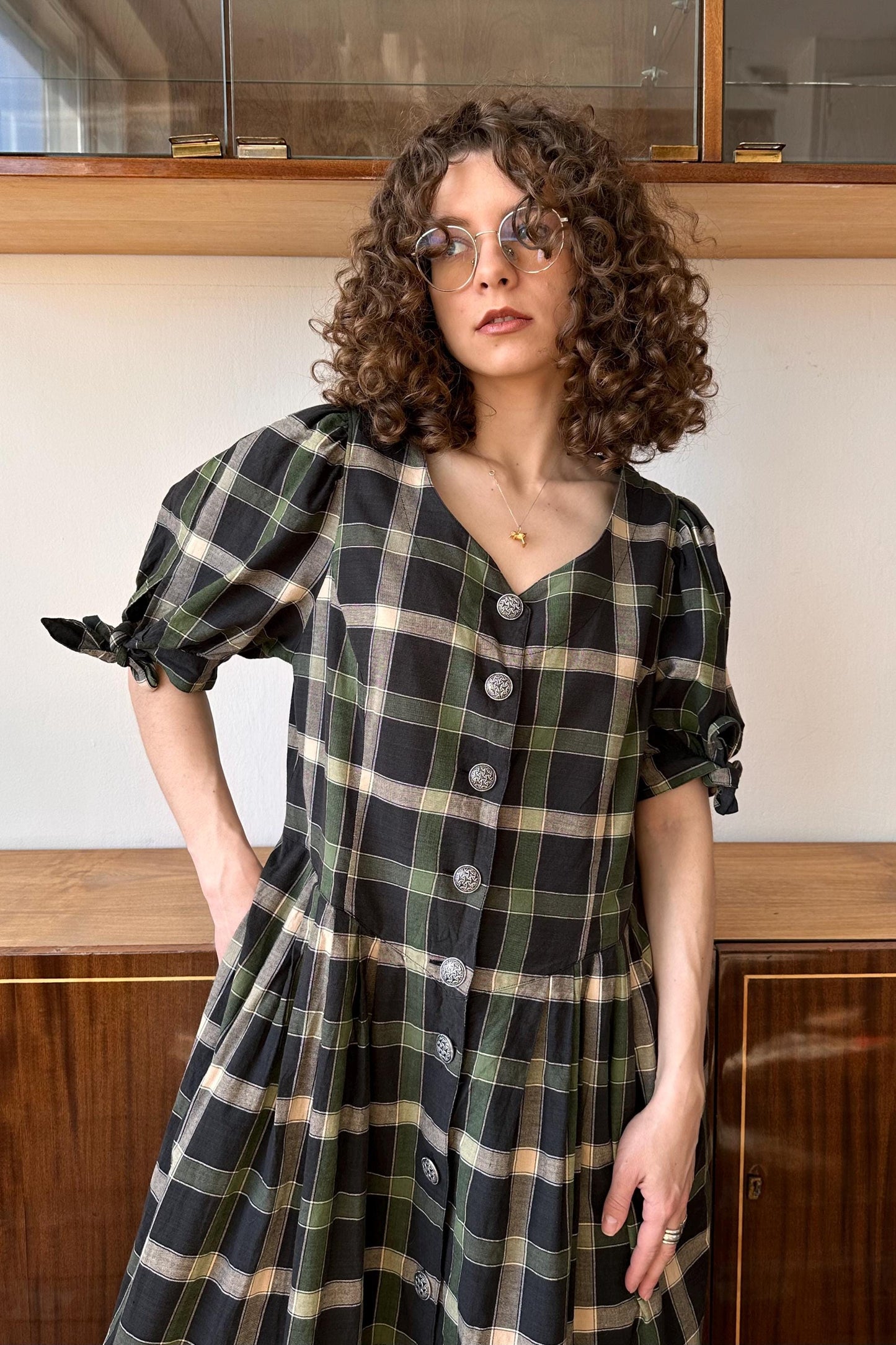 a woman with curly hair wearing a black and green plaid dress