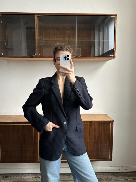 A person is taking a selfie with a smartphone in front of a wooden cabinet.
