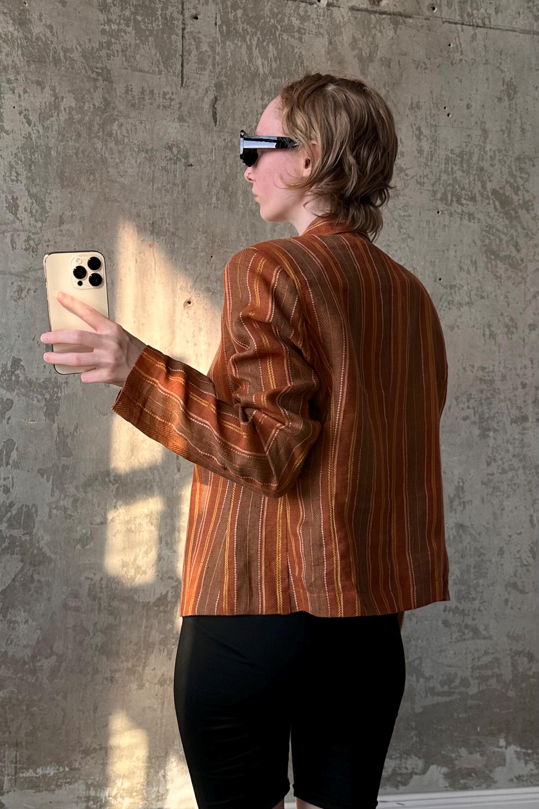 A person is standing in front of a concrete wall, holding a smartphone and taking a photo.
