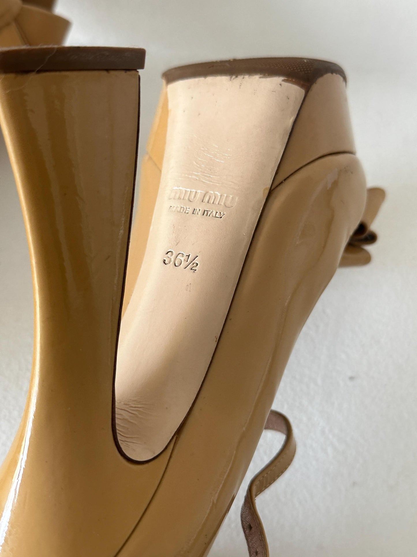 A close-up view of a beige high-heeled shoe, showing the heel and sole.