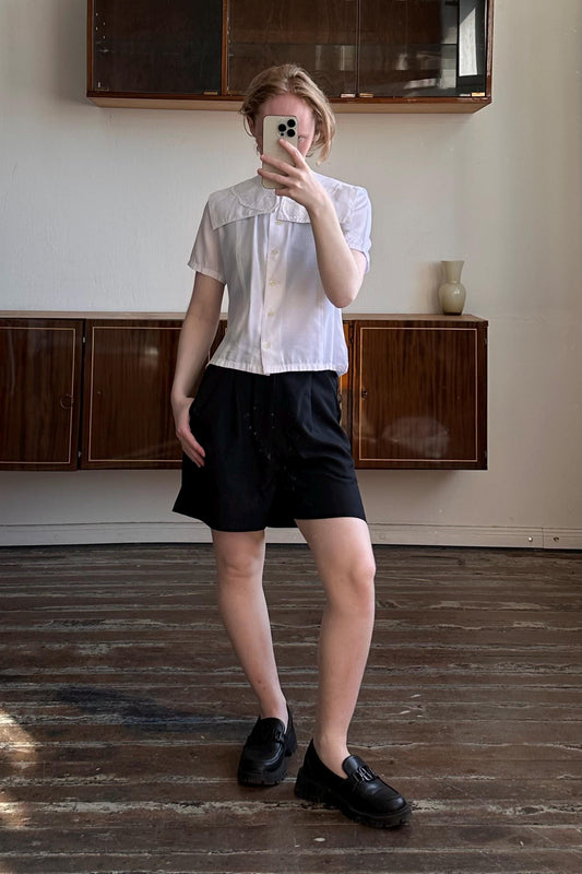 A person is taking a selfie in a room with wooden floors and a wooden cabinet.