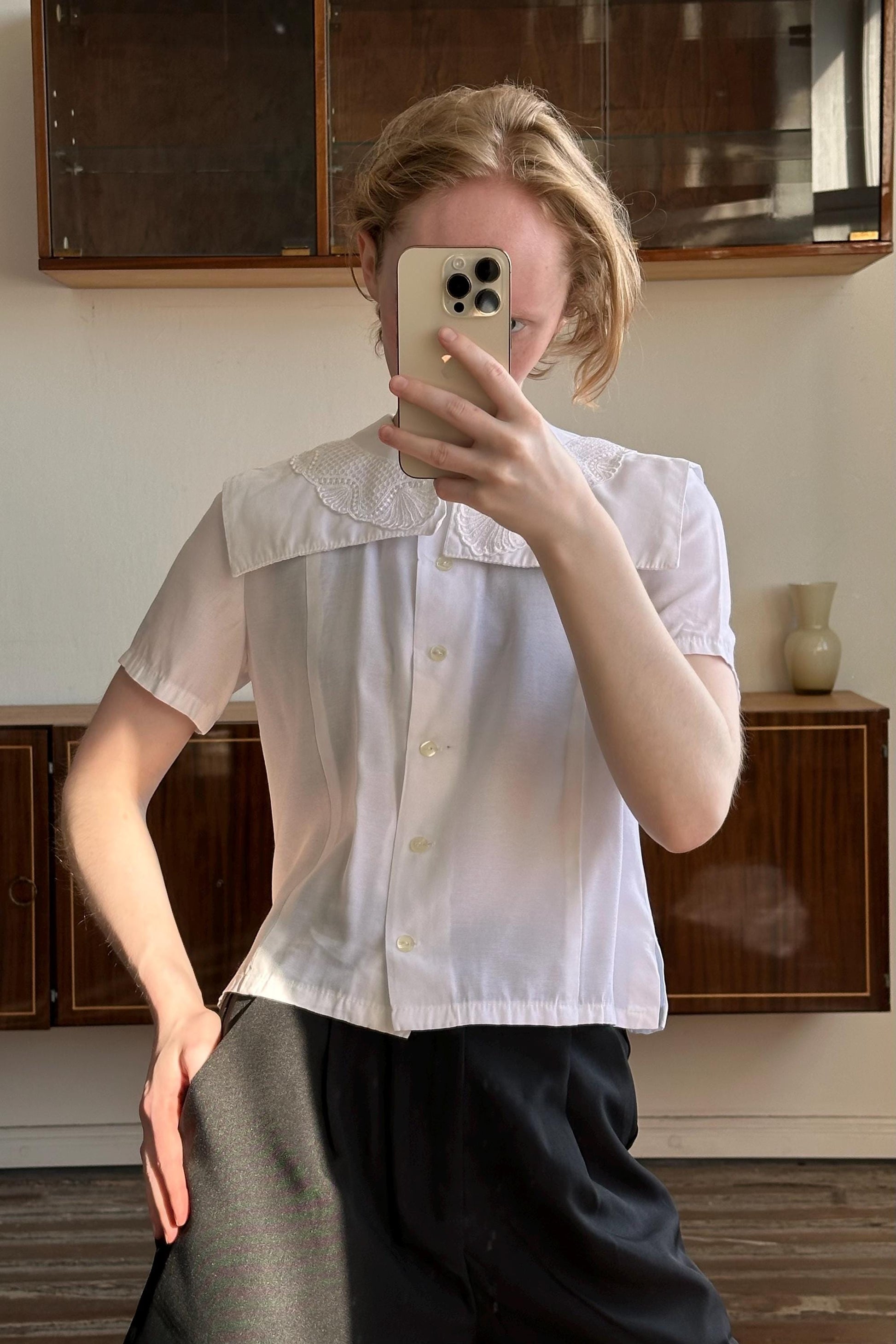A person is taking a selfie with a smartphone, holding the phone up to their face and covering their face.