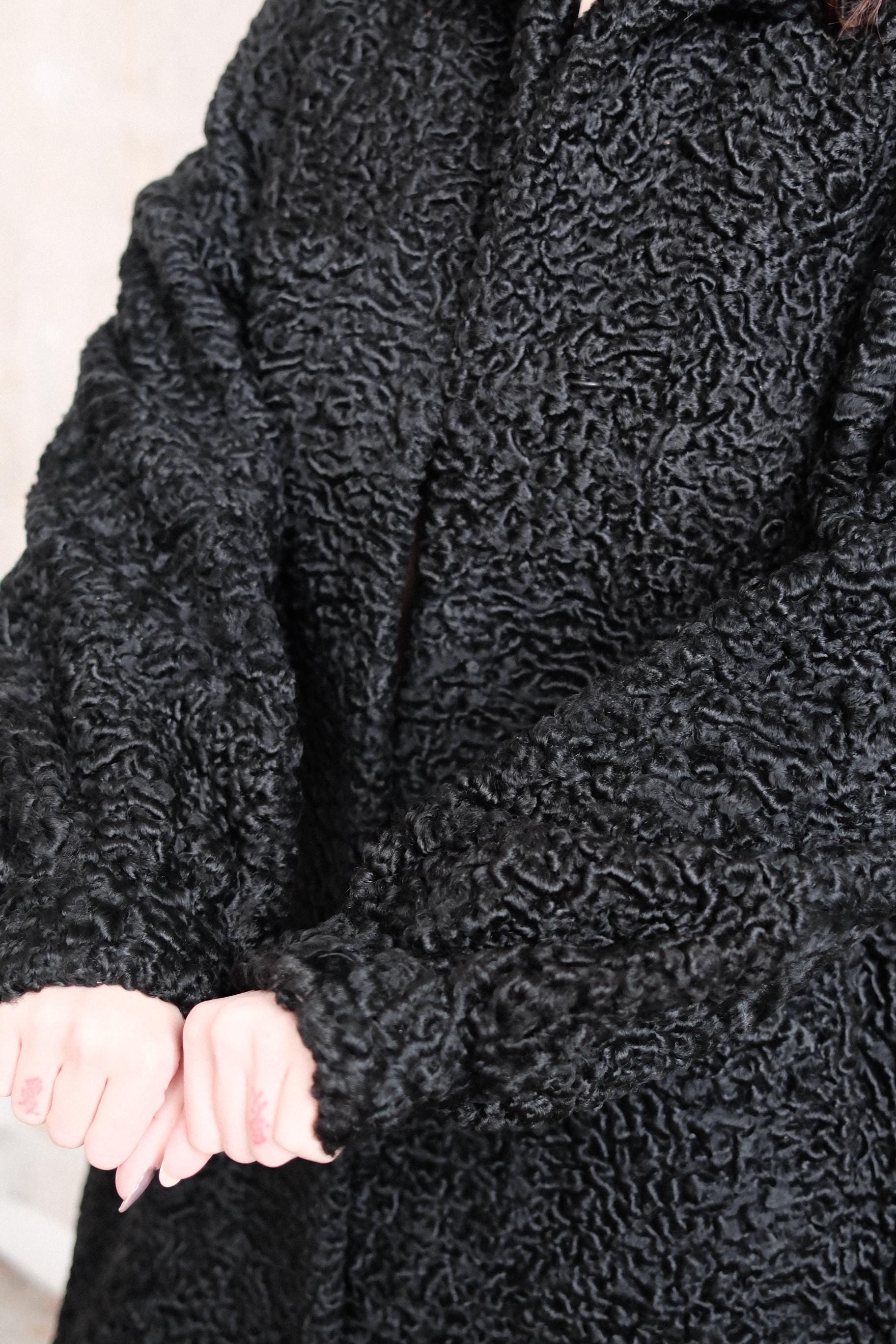 A close-up view of a black, furry fabric, possibly a type of wool or a similar material.