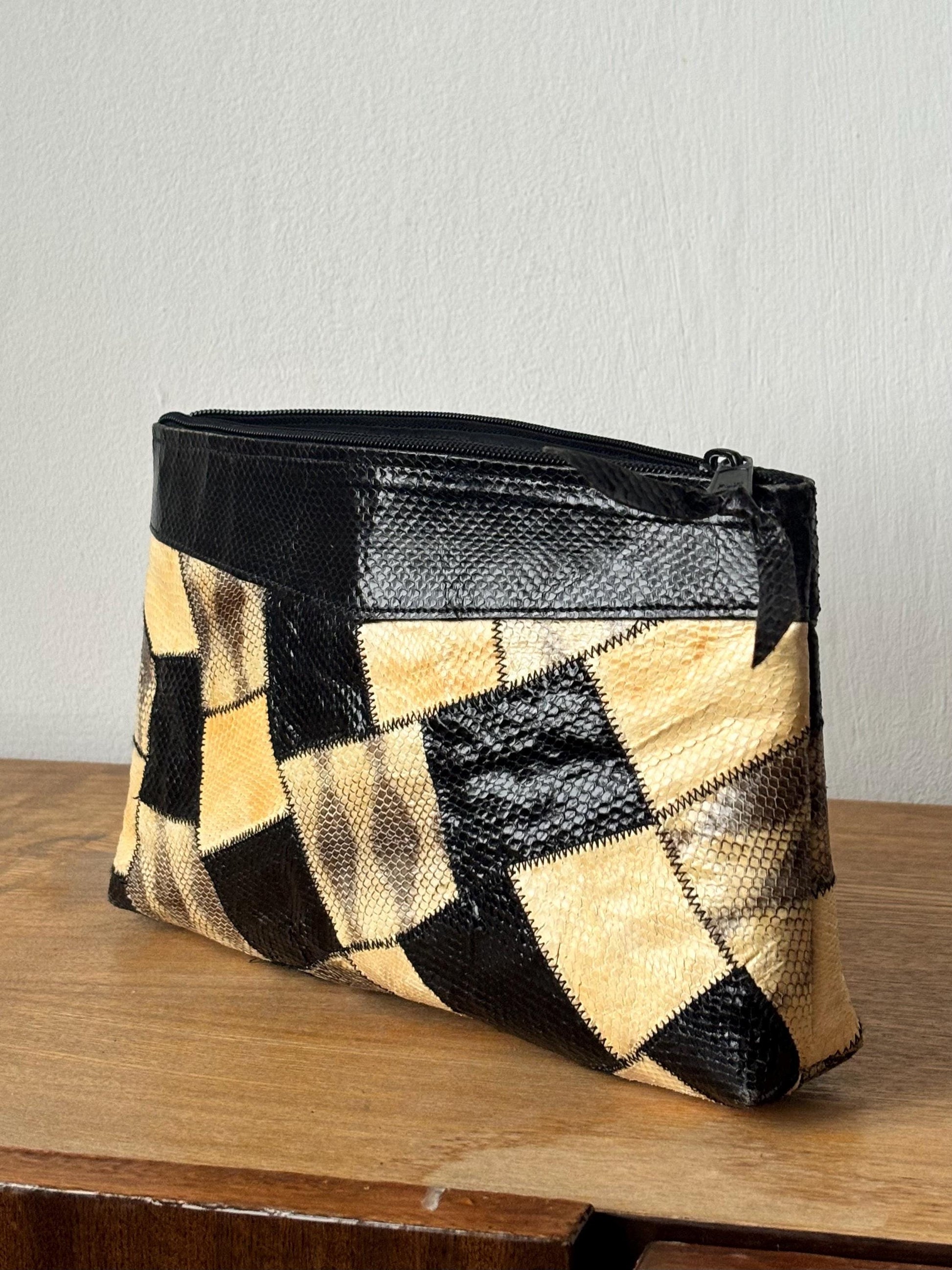 A black and tan patchwork bag with a zippered closure, sitting on a wooden surface.