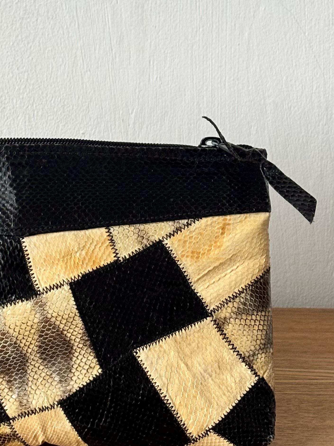 A black and tan patterned purse with a zipper closure.