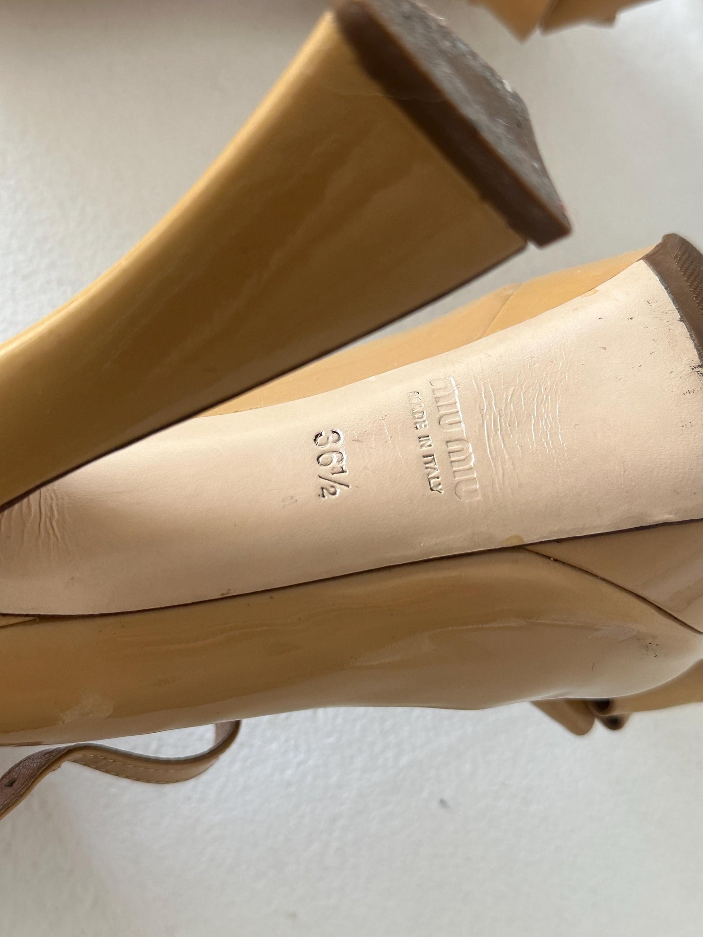 A close-up view of the heel and sole of a beige high-heeled shoe, with the brand name and size information printed on the heel.