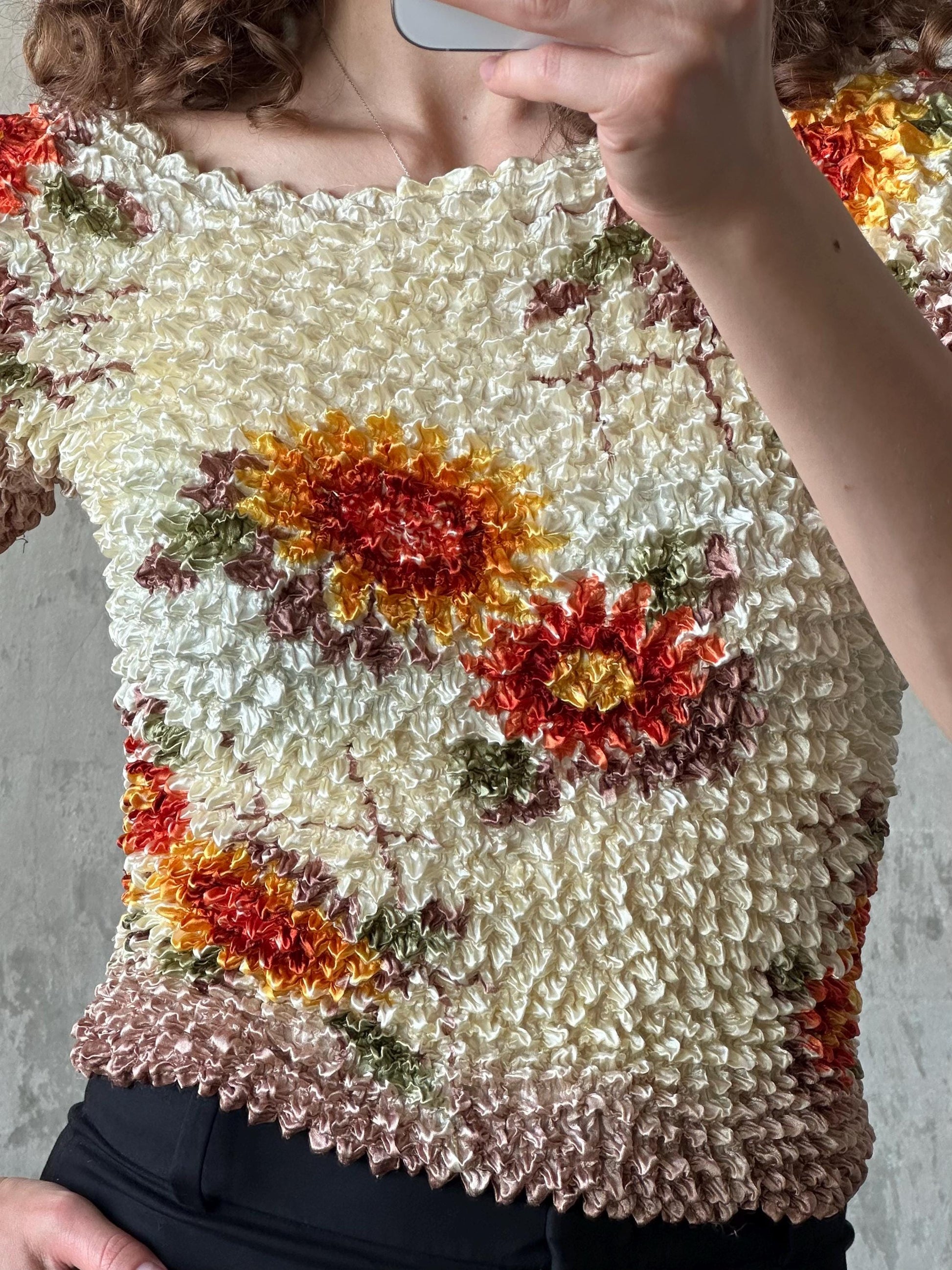 a close-up of a person taking a selfie with a floral patterned top.