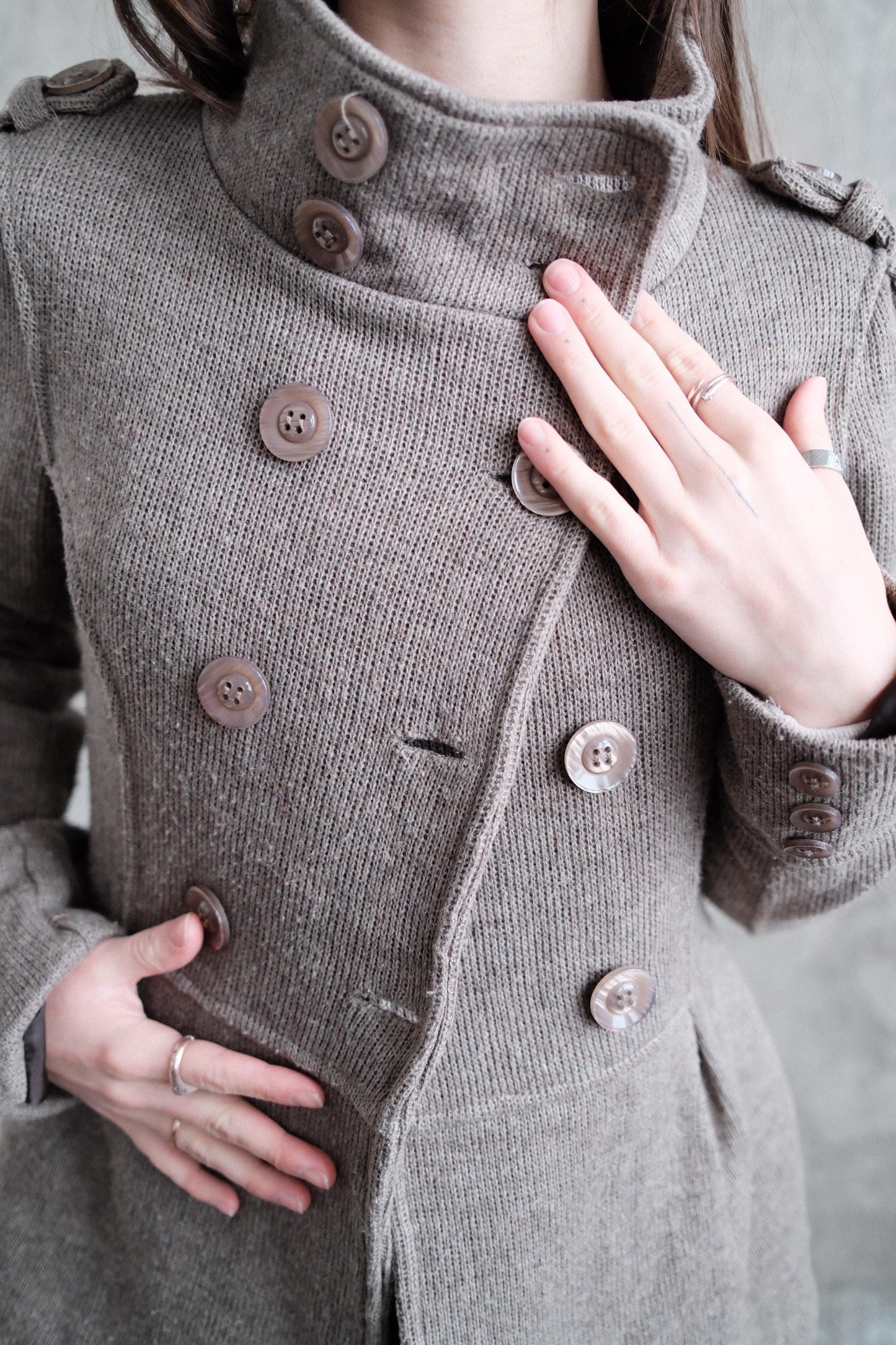 A close-up view of a person's torso wearing a gray double-breasted coat with buttons.